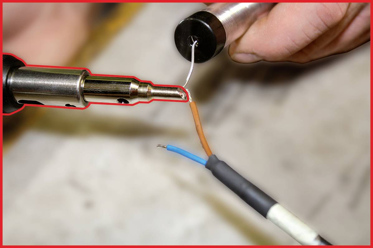 Zwei Drähte werden mit einem Lötkolben verbunden. Eine Hand hält die Drähte, während die andere den Kolben führt.