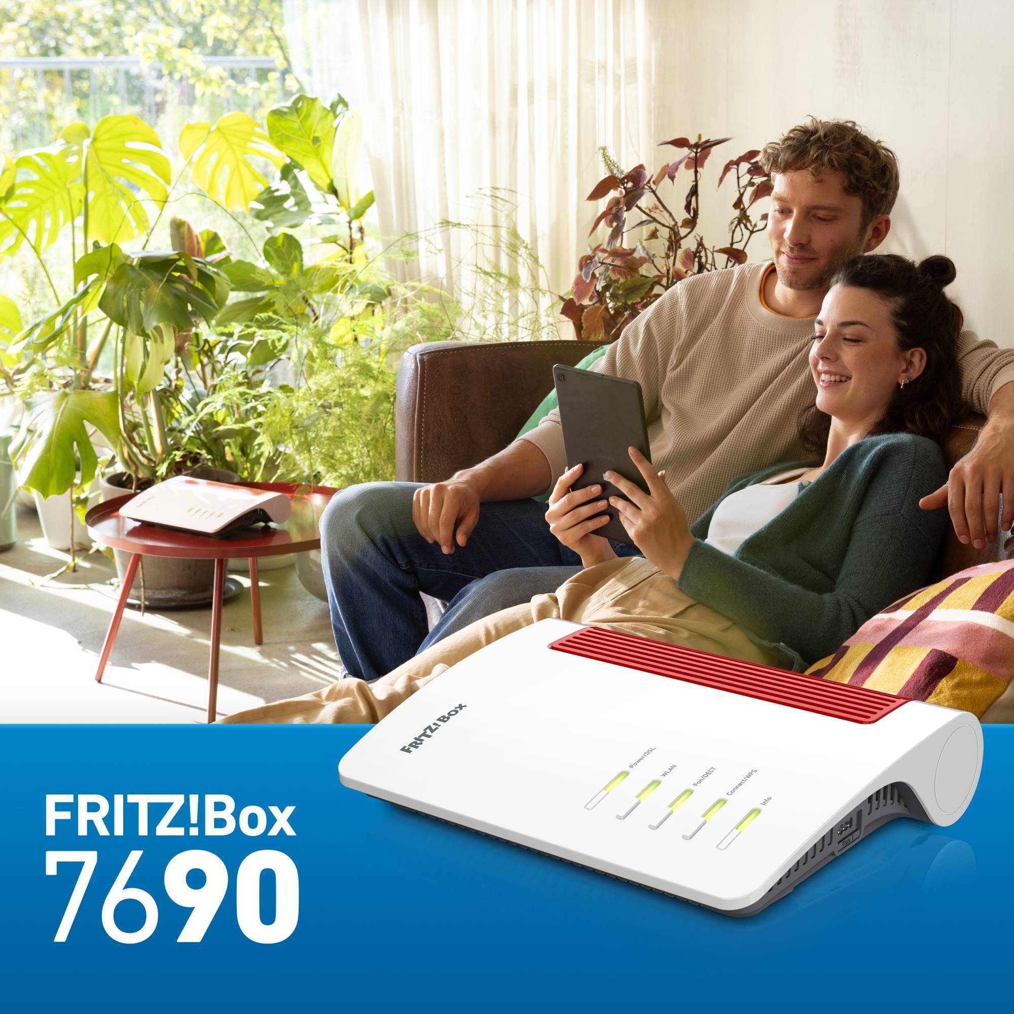 Ein Paar sitzt entspannt auf einem Sofa, schaut gemeinsam auf ein Tablet. Im Vordergrund ist eine FRITZ!Box 7690 abgebildet.