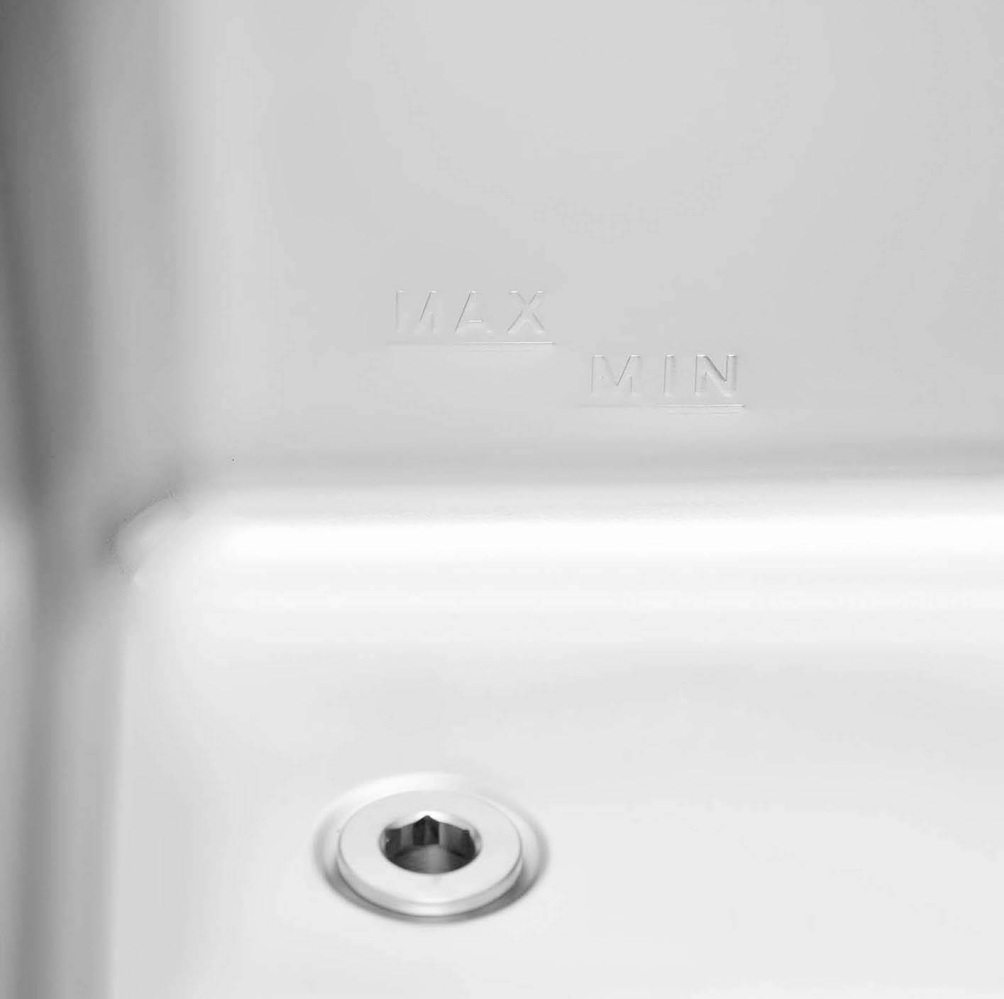 Nahaufnahme eines Waschbeckens mit einem Abfluss. Neben dem Abfluss sind die Worte 'MAX' und 'MIN' eingraviert, die maximale und minimale Füllhöhe anzeigend.