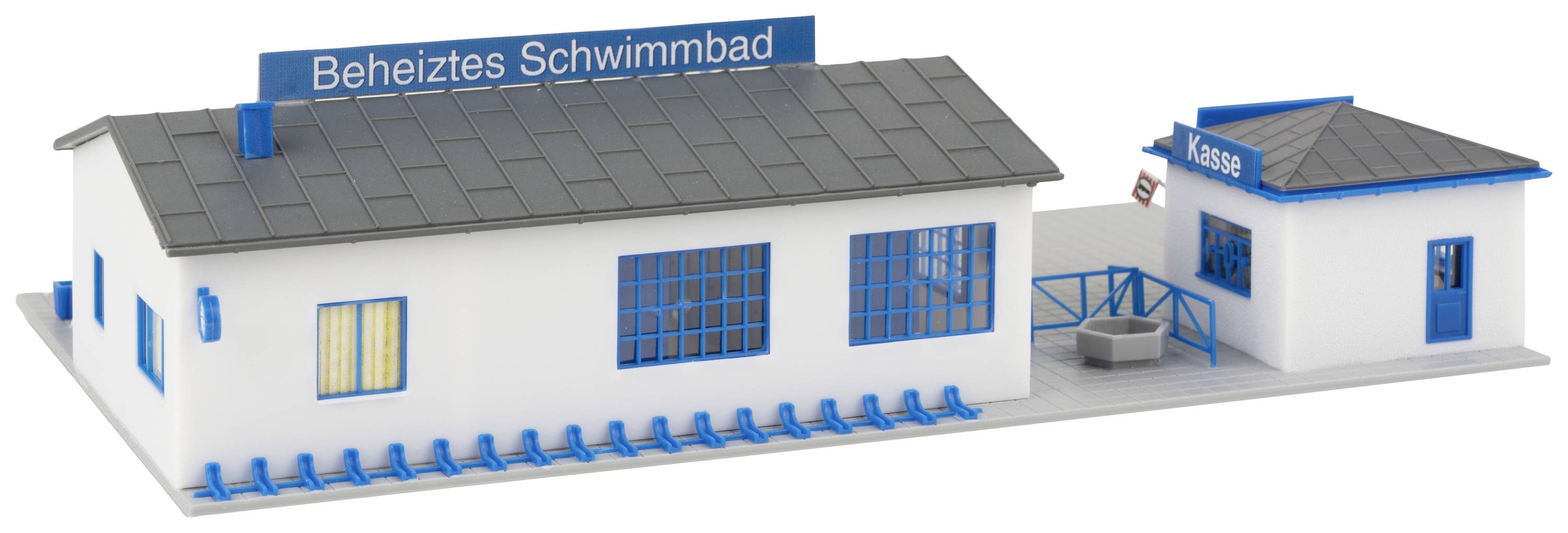Ein Miniaturmodell eines beheizten Schwimmbads mit Hauptgebäude, blauem Schild und kleinem Kassenhäuschen.