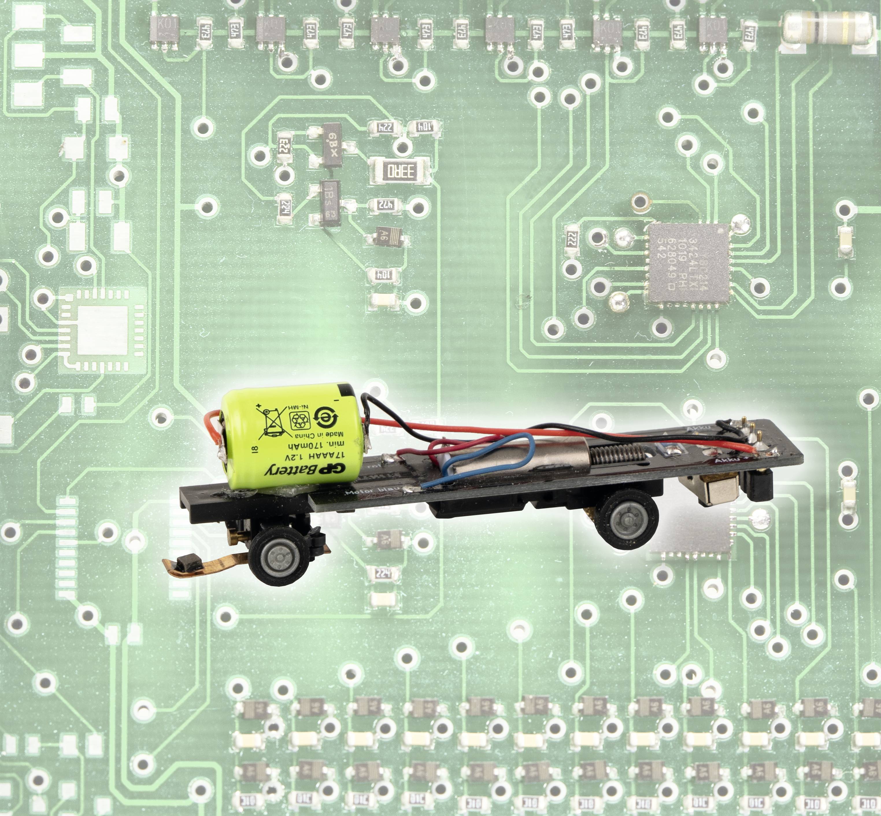 Ein Modellbahndecoder mit Kabeln und einem gelben Kondensator ist auf einer grünen Leiterplatte montiert.