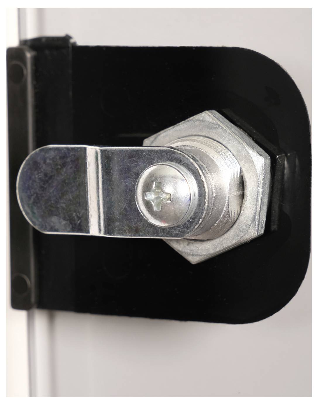 Silbernes Riegelschloss an einer schwarzen Halterung, befestigt an einer weißen Oberfläche. Das Schloss ist sechseckig geformt.