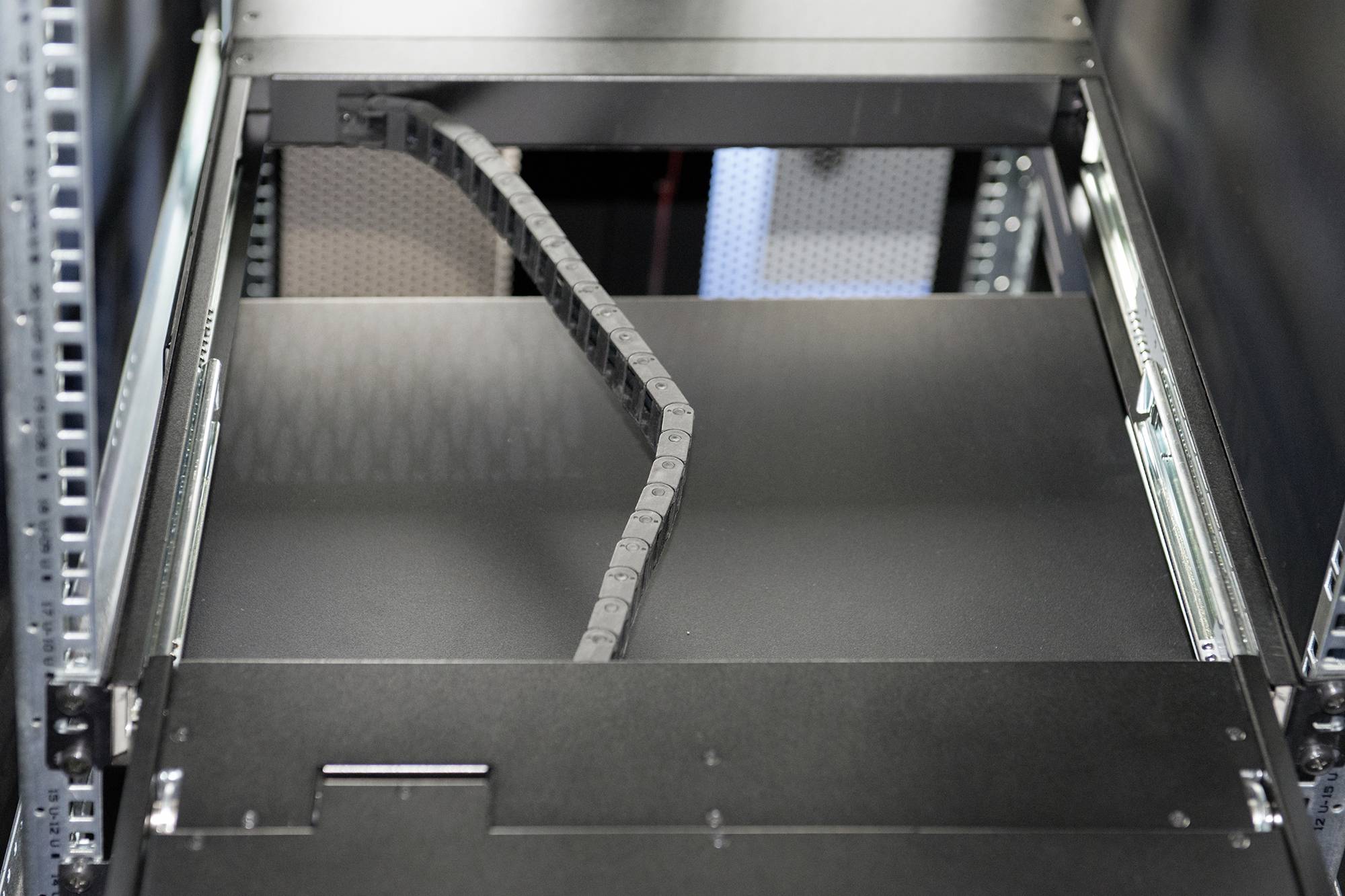 Ein leeres Server-Rack in einem Datenzentrum, bereit zur Installation von Hardware. Metallische Leitungen und Verbindungen sichtbar.