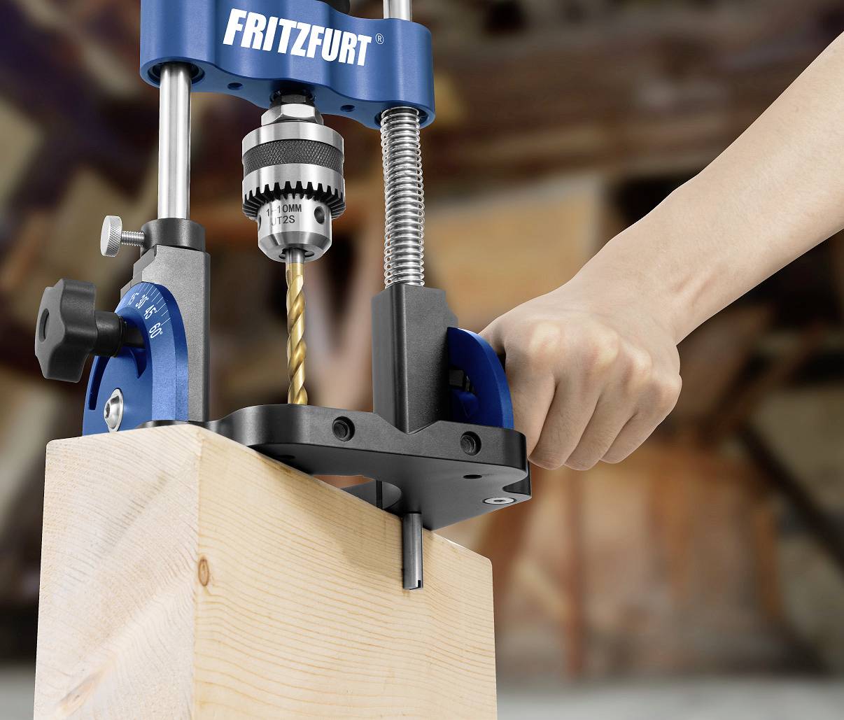 Hand bedient eine blaue Ständerbohrmaschine, die ein Loch in einen Holzblock bohrt. Hintergrund ist unscharf.