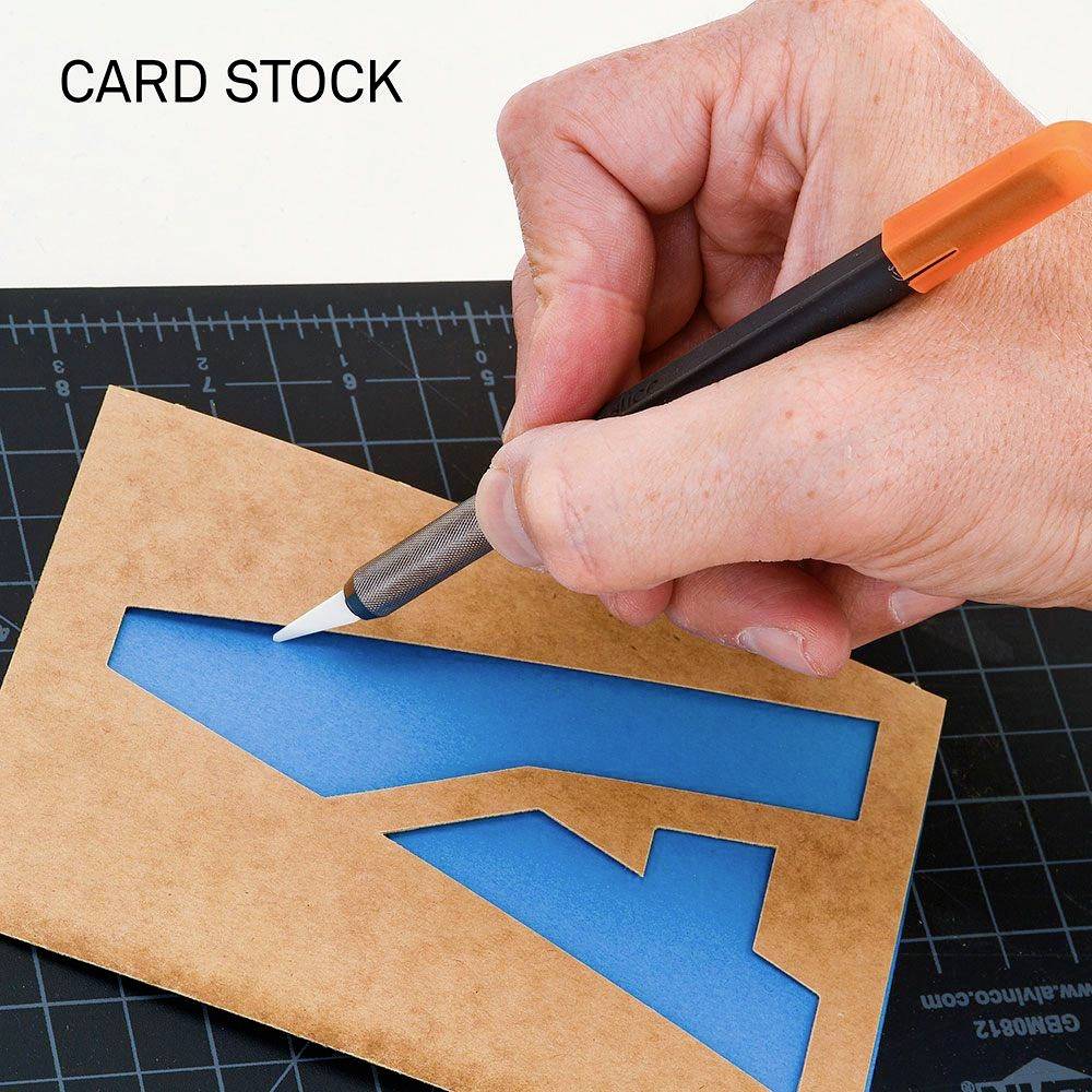 Eine Hand schneidet mit einem Messer ein Formular auf Kartonpapier. Links oben steht 'CARD STOCK'.