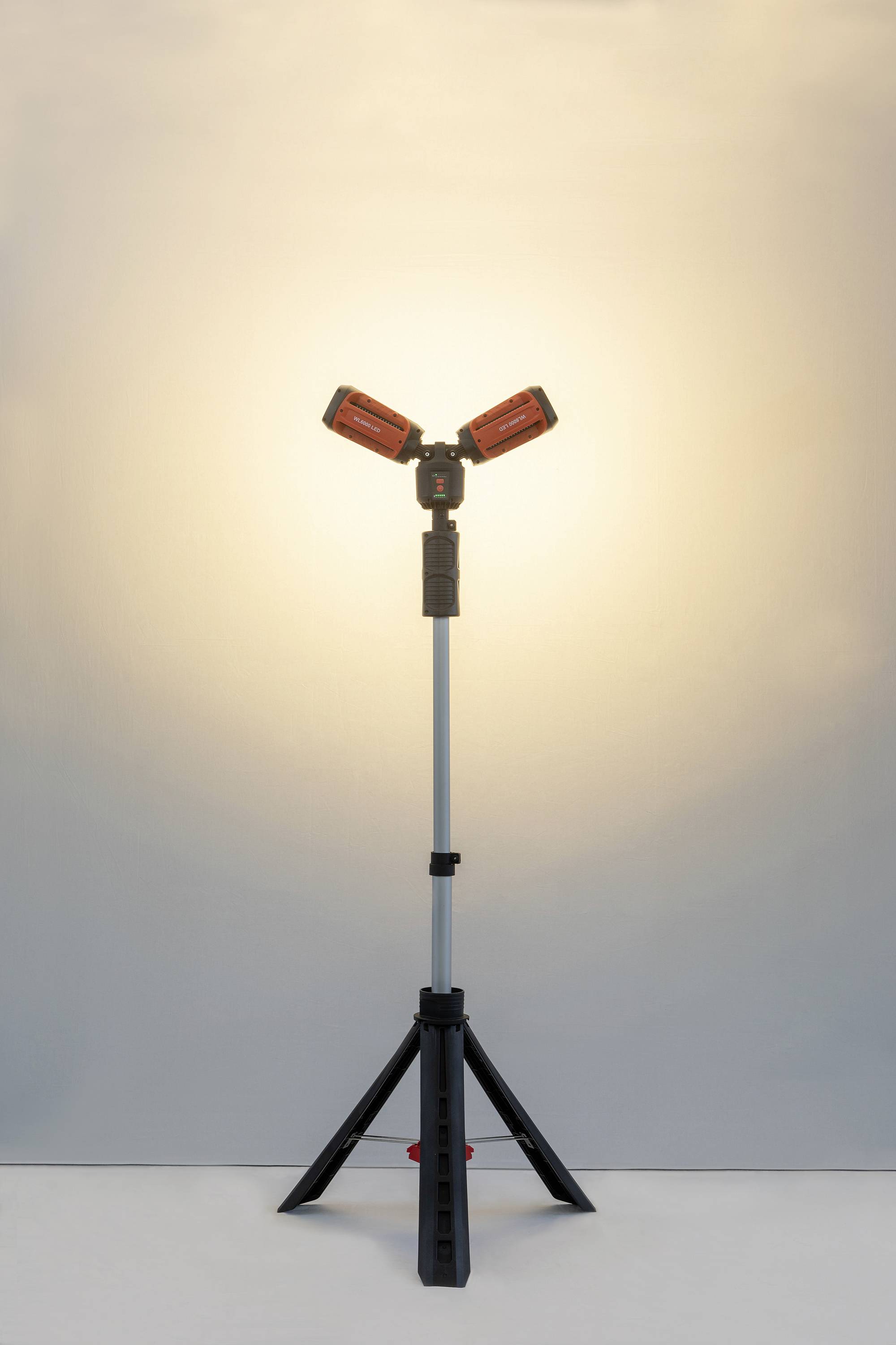 Eine duale LED-Arbeitsleuchte auf einem dreibeinigen Stativ leuchtet einen Raum mit warmem Licht aus, geeignet für Bauprojekte.