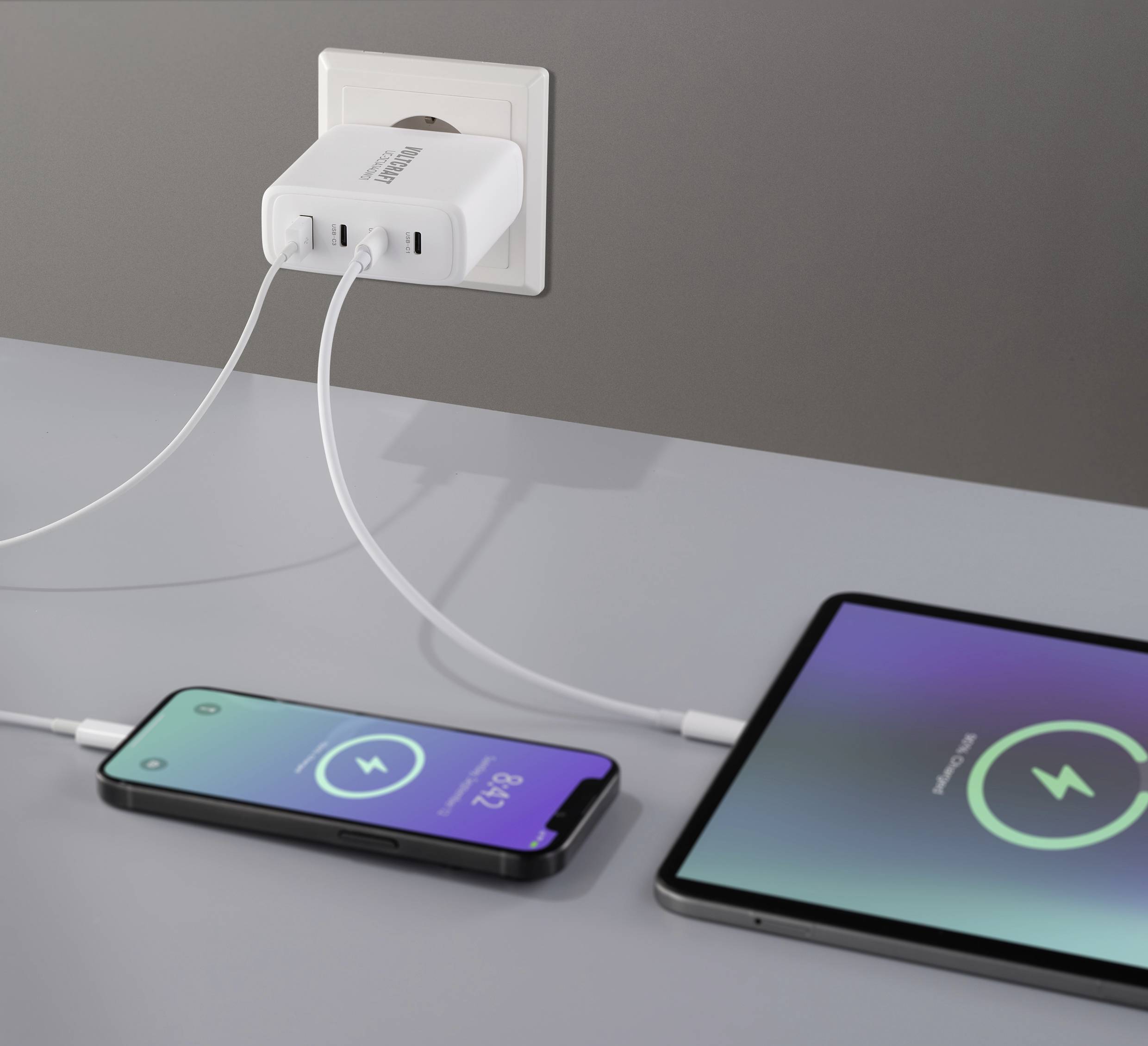 Ein Ladegerät mit zwei angeschlossenen Smartphones zeigt Ladesymbole auf den Displays, die den Ladevorgang anzeigen.