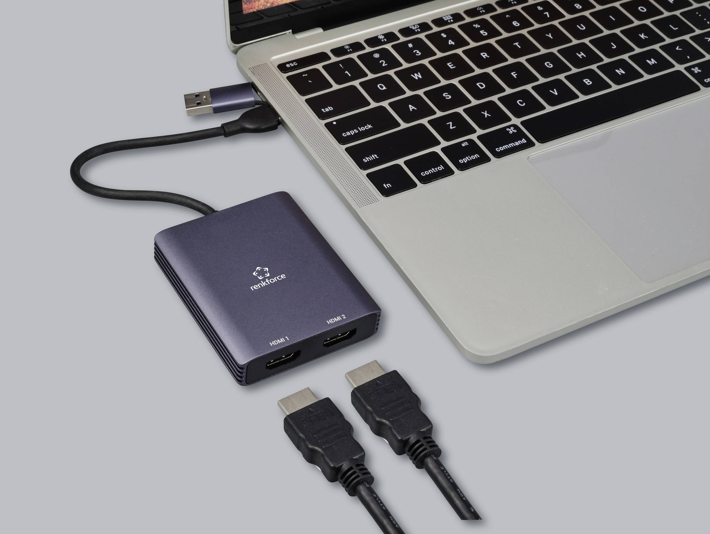 Ein Laptop ist mit einem HDMI-Splitter verbunden, der zwei HDMI-Ausgänge hat. Zwei HDMI-Kabel liegen daneben bereit.