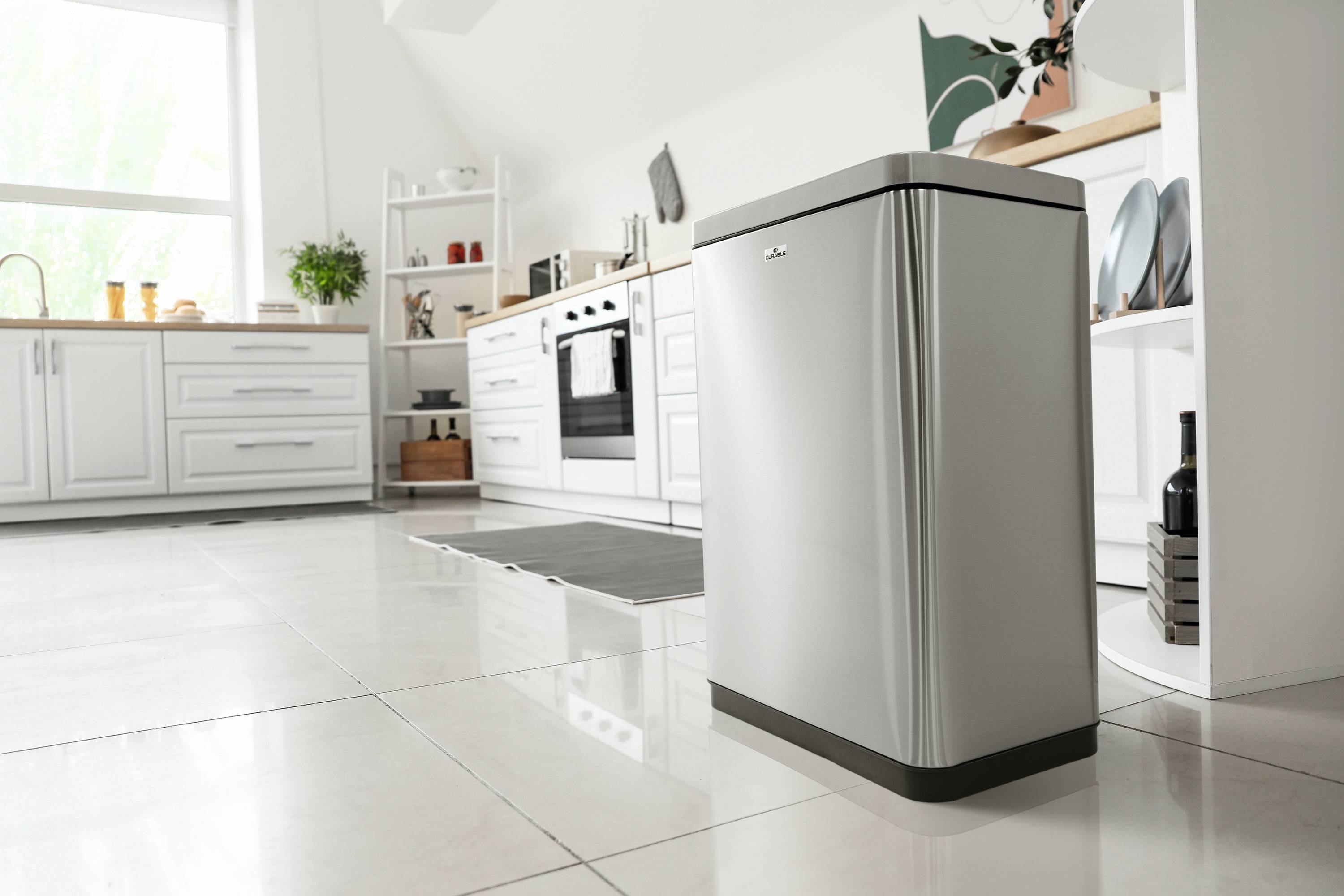 Moderne Küche mit weißem Interieur und edelstahlsilbernem freistehendem Kühlschrank im Vordergrund. Helle Dekoration und Kochutensilien.