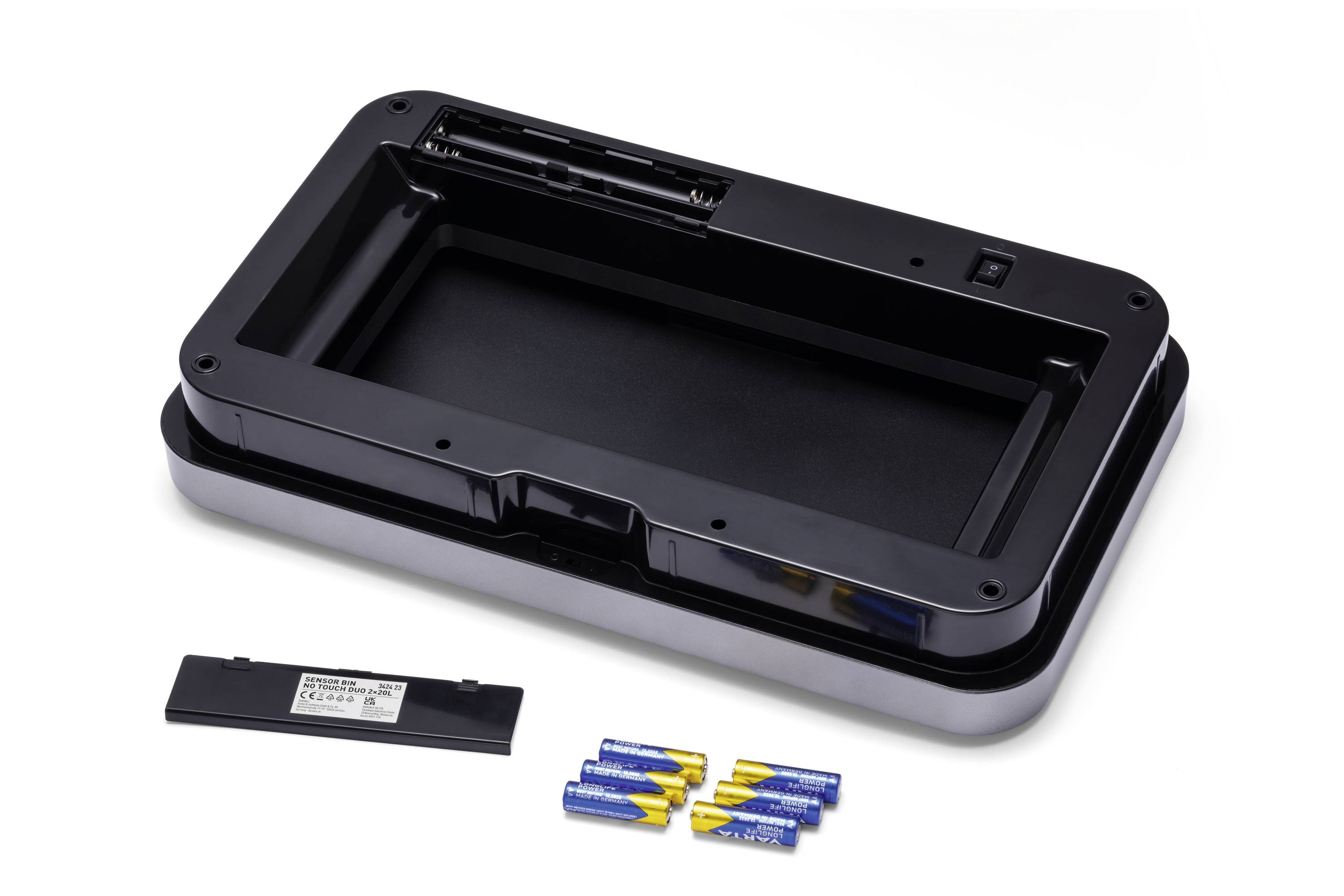Ein geöffneter Batteriefachdeckel eines Geräts mit acht blauen Batterien daneben. Der Deckel liegt auf einem weißen Hintergrund.