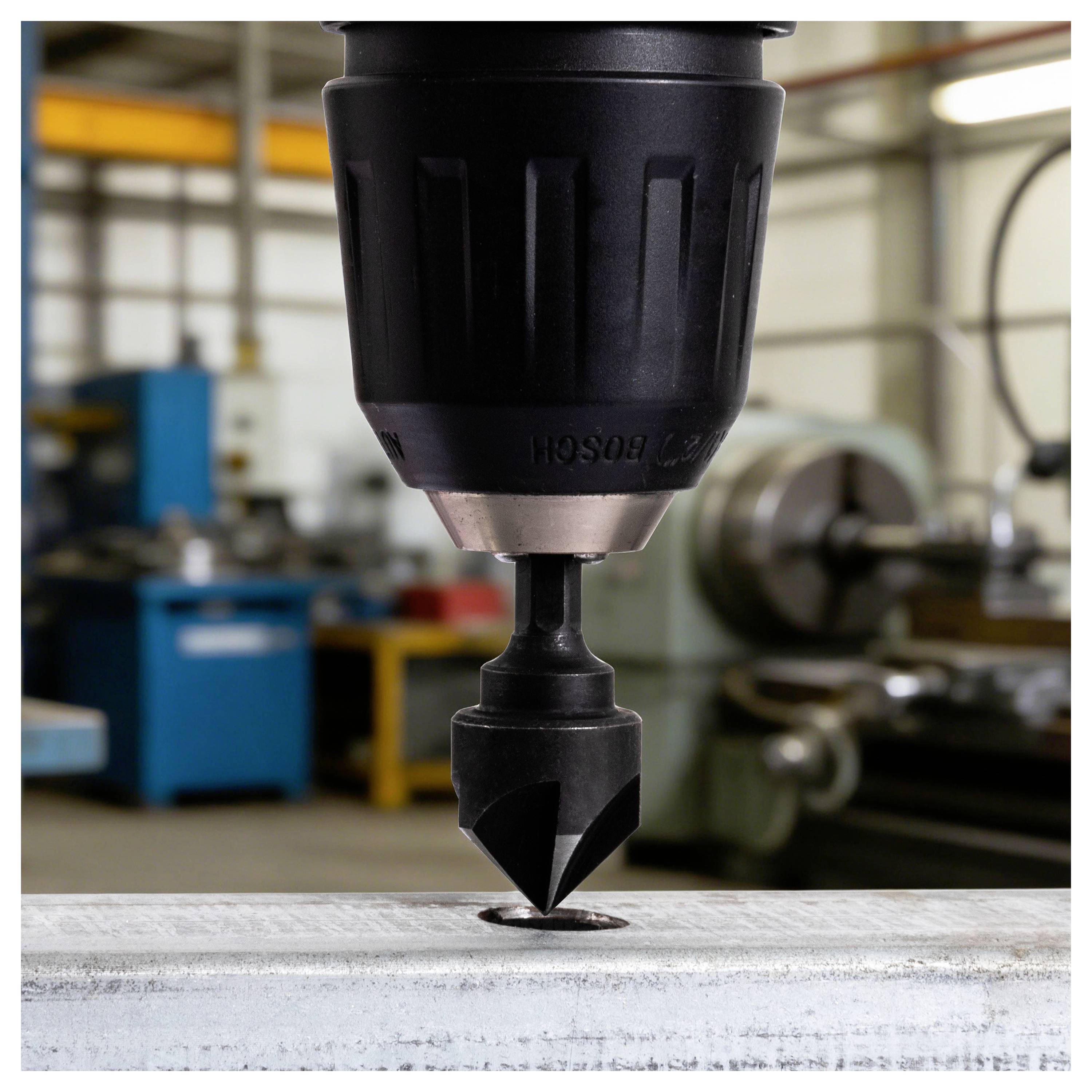 Nahaufnahme eines Bohrmaschinen-Bohrers, der in ein Metallwerkstück in einer Werkstatt eindringt.