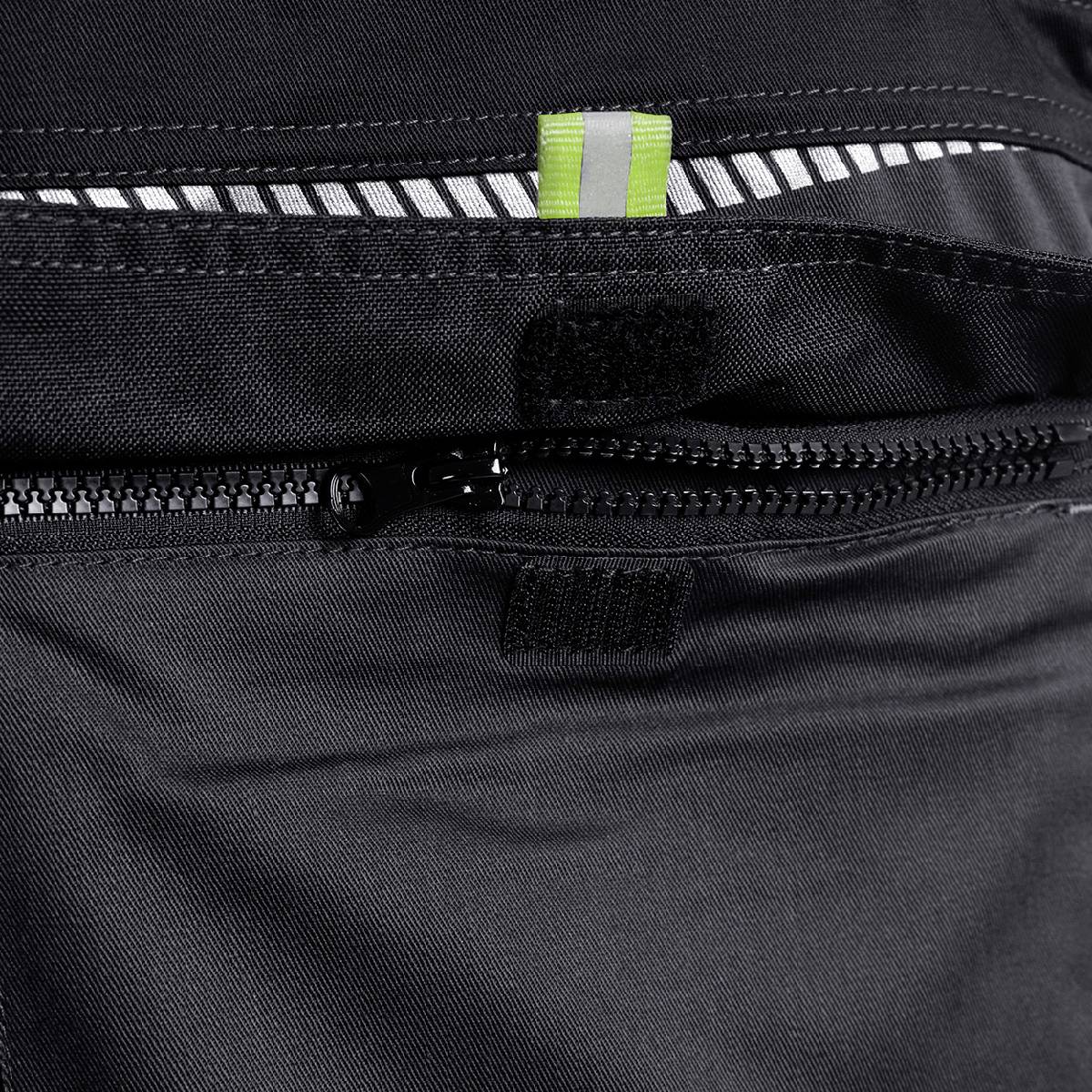 Schwarze Tasche aus Stoff mit Reißverschluss, geöffnet. Oben ist ein Strukturmuster aus weißen und grünen Streifen zu sehen.