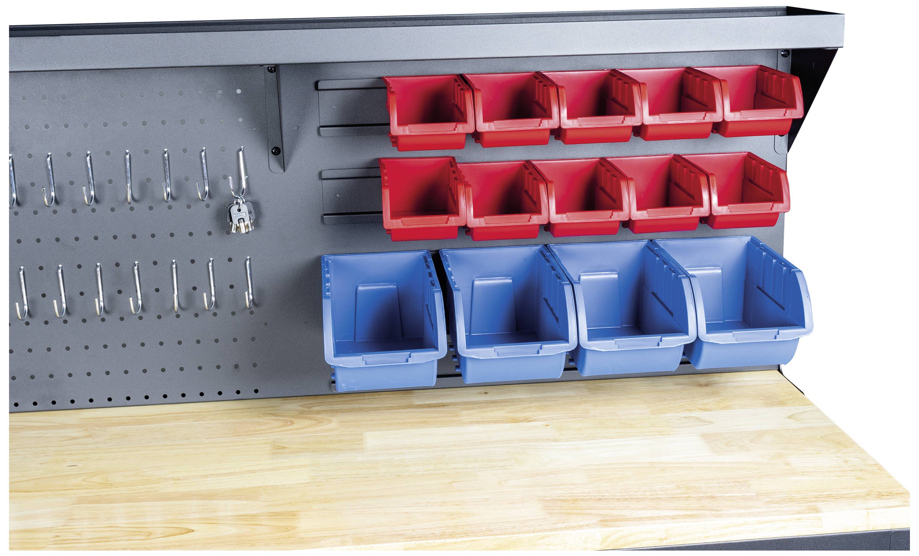 Werkbank mit Lochwand, roten und blauen Kunststoffkisten zur Aufbewahrung von Werkzeugen. Holztischplatte unten im Bild.
