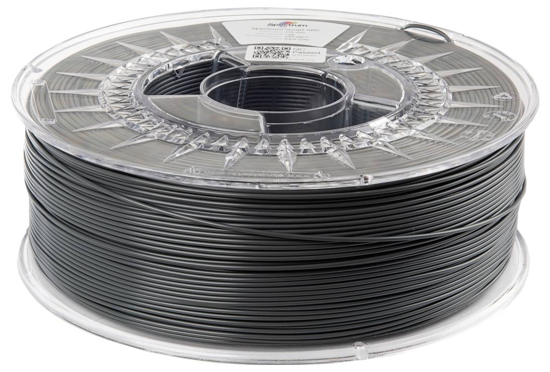 Eine transparente Spule mit schwarzem 3D-Druckerfilament, auf einer sauberen, weißen Oberfläche liegend.