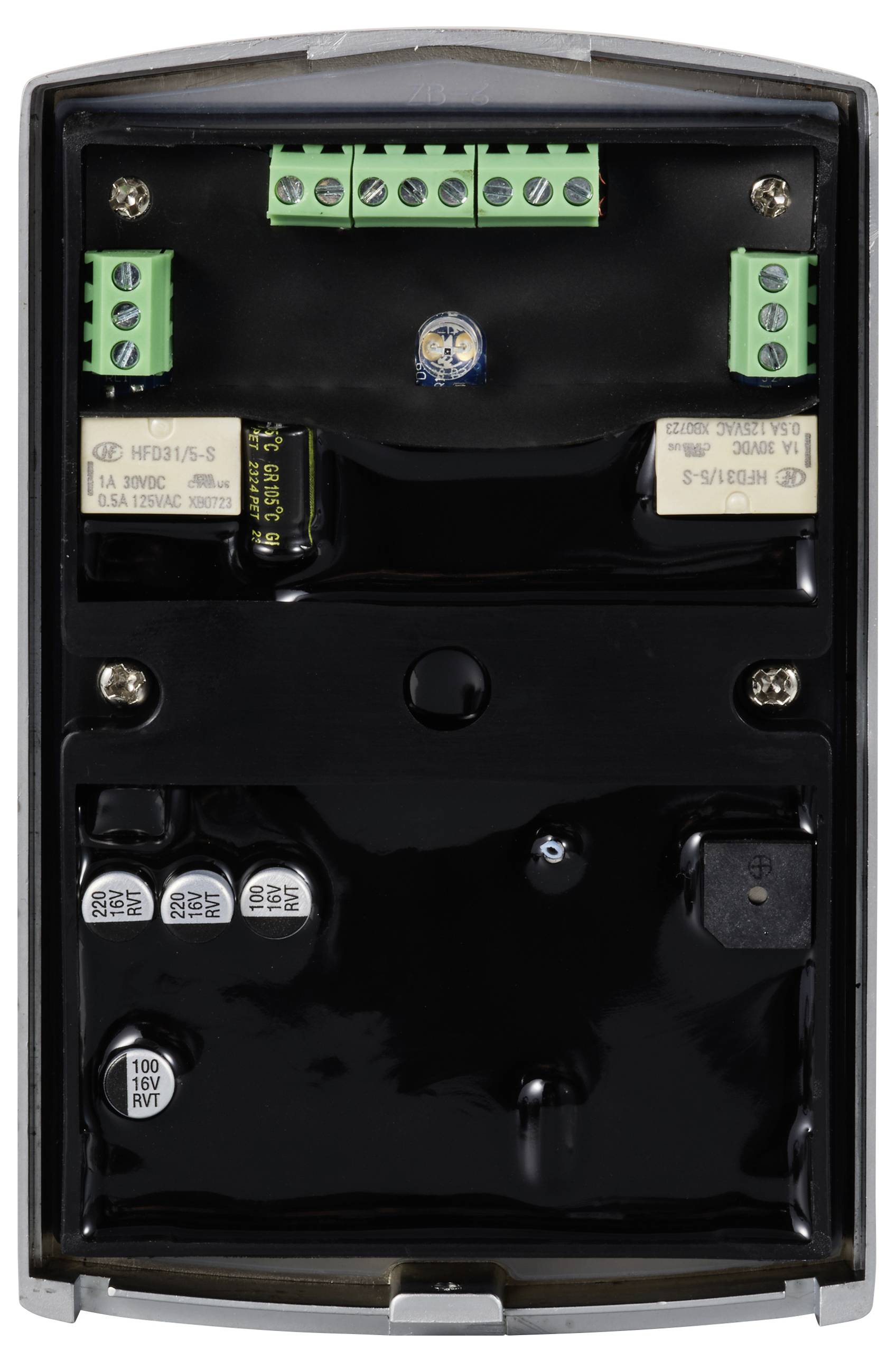 Ein offenes elektronisches Gerät mit mehreren grünen Klemmen und schwarzen Komponenten auf einer schwarzen Platine, dicht angeordnet.