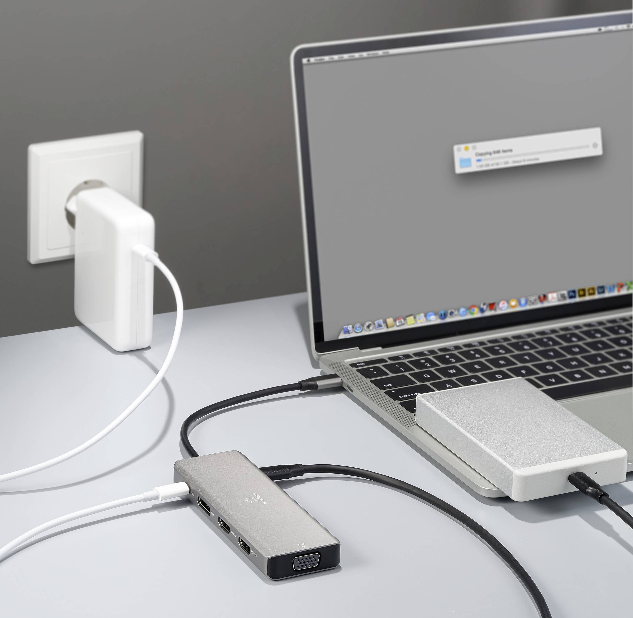 Ein Laptop ist über mehrere Kabel und Adapter an eine Steckdose angeschlossen. Ein graues Fenster erscheint auf dem Bildschirm.