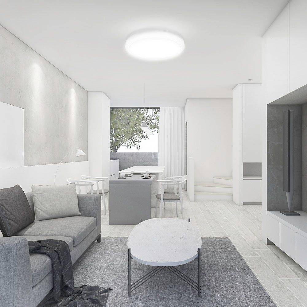 Helles, modernes Wohnzimmer mit grauem Sofa, weißem Tisch und großem Fenster. Außenbereich mit Baum sichtbar. Minimalistischer Stil.