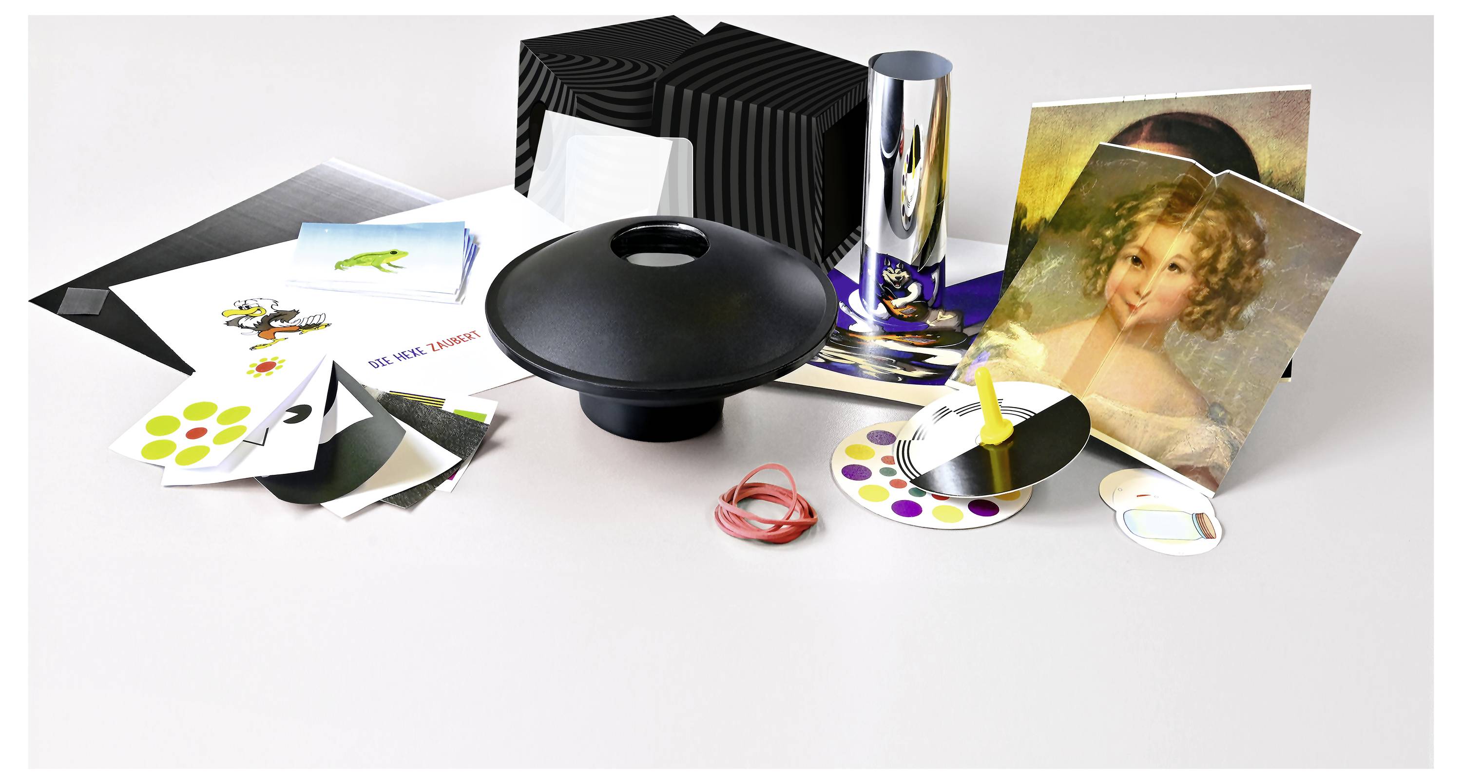 Eine Sammlung von Drucken, Fotos und Farbmusterkarten, umgeben von einem schwarzen Kopfhörer und Gummibändern auf einem Tisch.