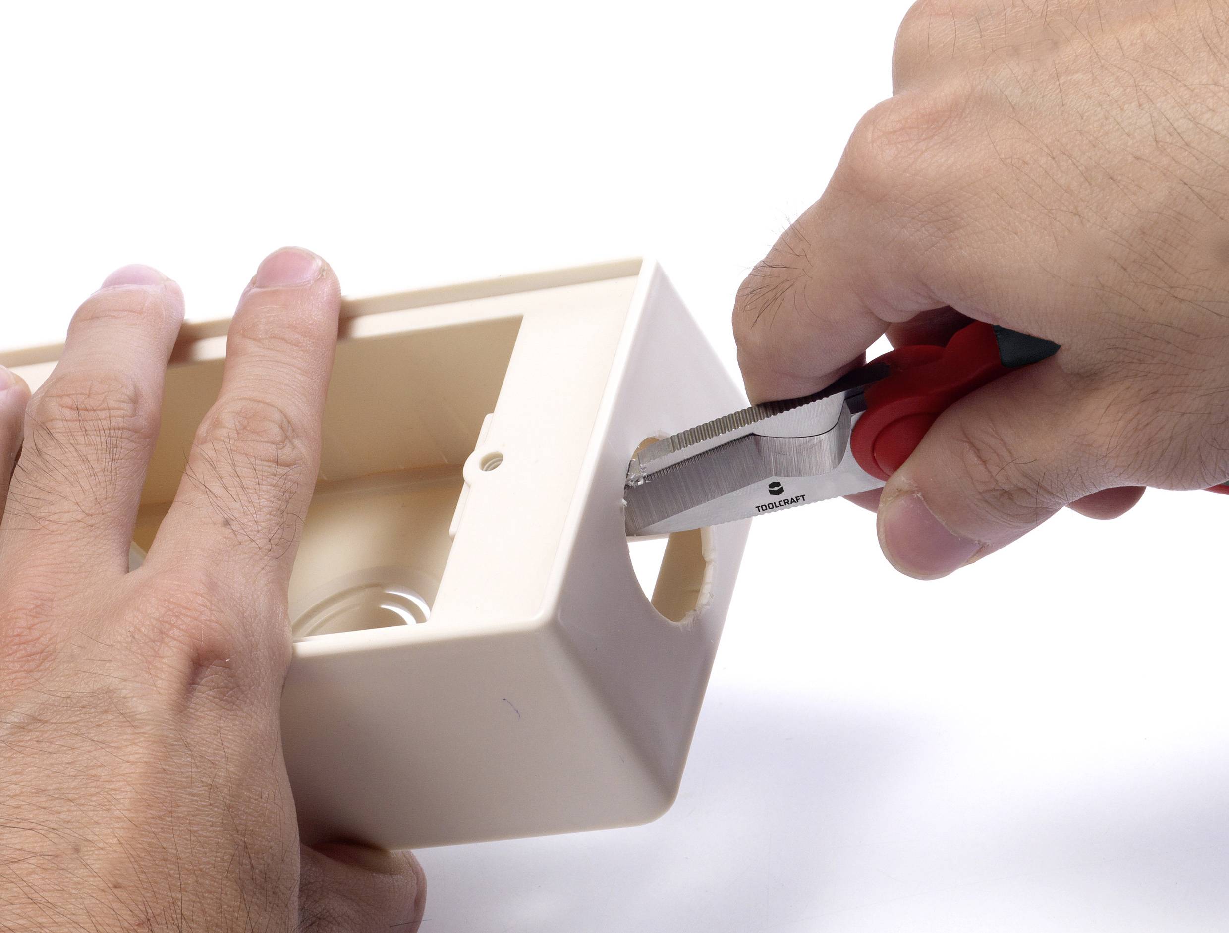 Eine Person benutzt einen Drahtschneider, um ein Loch in eine Kunststoffbox zu schneiden. Die Box wird mit der anderen Hand gehalten.