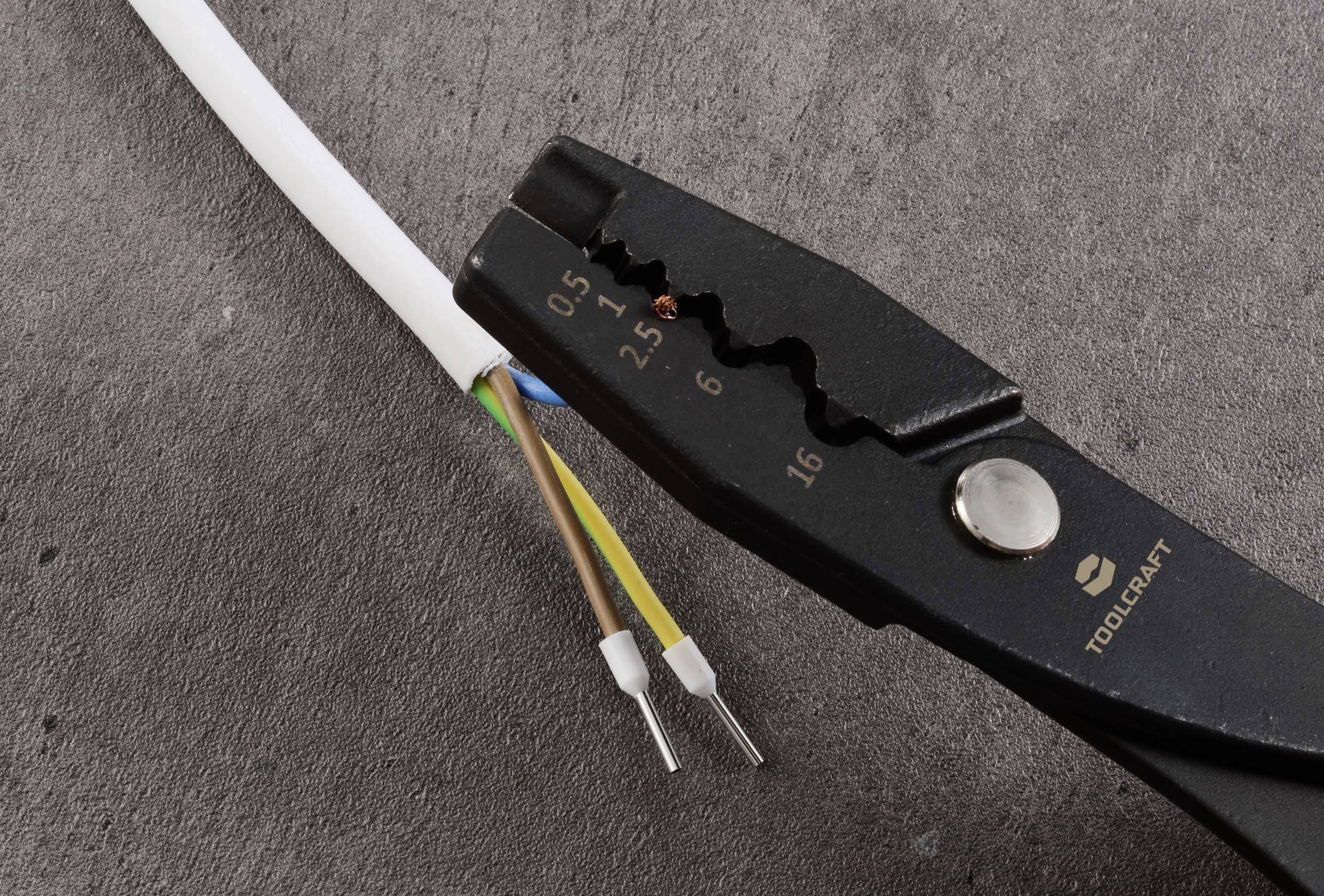 Ein Kabel wird von einer Abisolierzange gehalten, die drei freiliegende Adern zeigt.