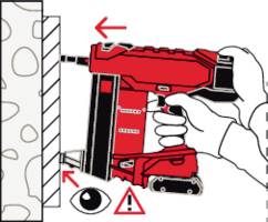 Die Grafik zeigt Hände, die eine rote Bohrmaschine an einer Wand halten. Pfeile und Symbole weisen auf Vorsicht und Schutzmaßnahmen hin.