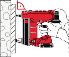 Eine Person hält ein rotes Werkzeug, um Befestigungselemente in eine Wand zu setzen.