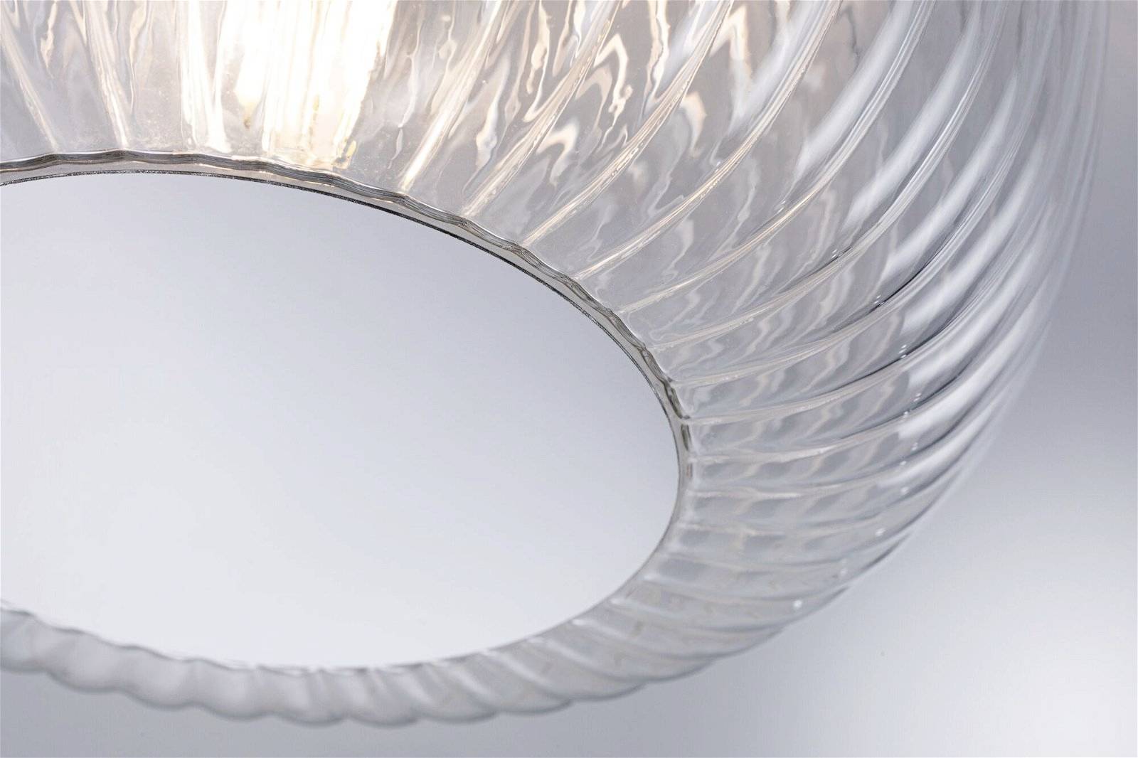 Eine transparente, strukturierte Glasleuchte hängt von der Decke und strahlt weiches, diffuses Licht aus.