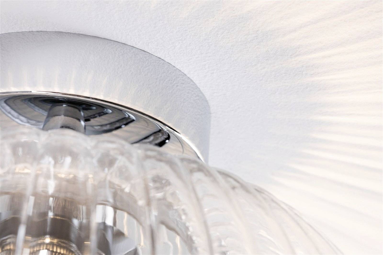 Deckenleuchte mit geriffeltem Glas, die weiches Licht mit strahlenförmigem Muster an die Decke wirft. Modernes Design.