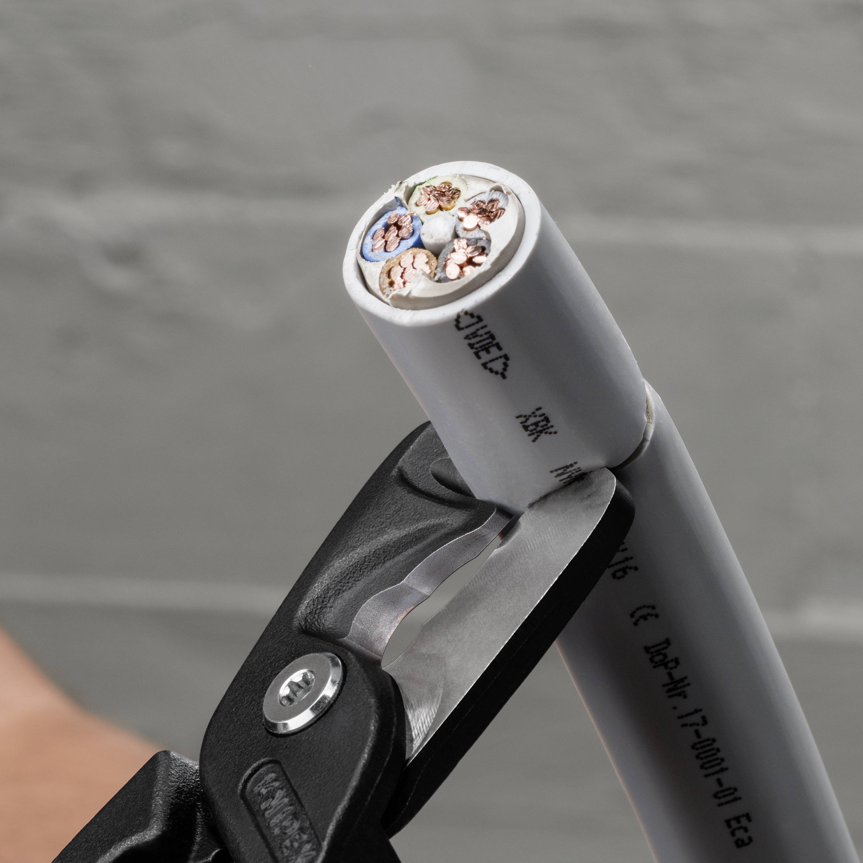 Ein Kabel wird mit einem Werkzeug durchtrennt, das die bunten Drähte im Inneren zeigt. Der Fokus liegt auf der Präzision des Schnitts.