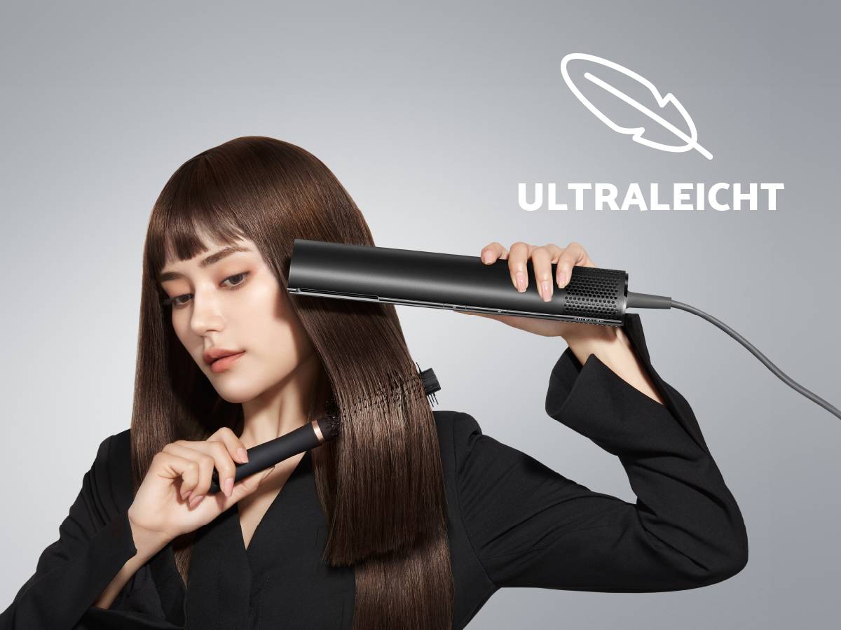 Eine Frau glättet ihr langes, glattes Haar mit einem Haarglätter. Daneben steht 'ULTRALEICHT'. Der Hintergrund ist grau.