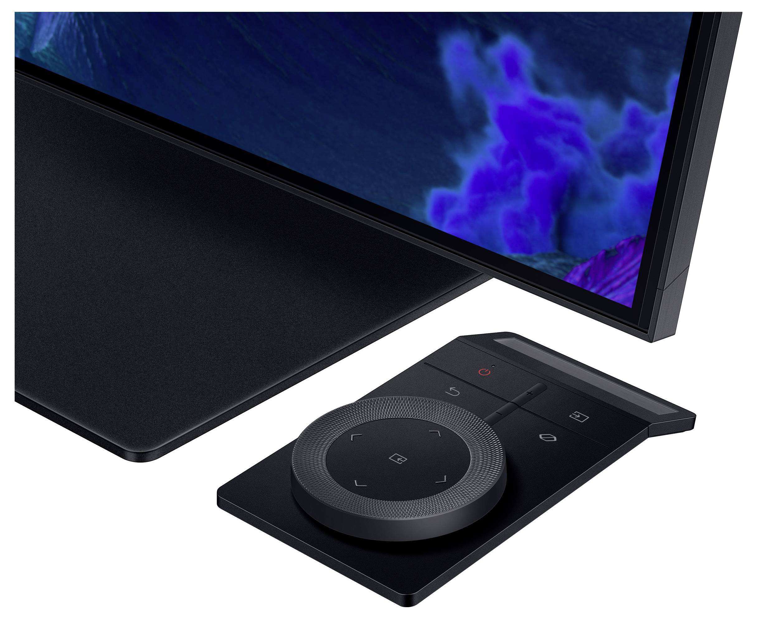 Ein schwarzer elektronischer Controller mit kreisförmigem Tastenfeld liegt neben einem Bildschirm, der blaue und violette Töne anzeigt.