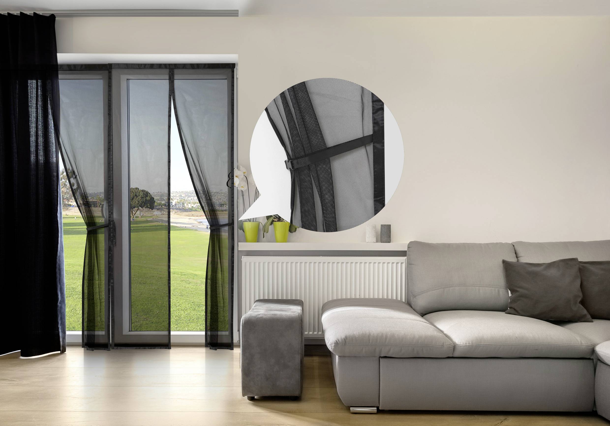 Ein Wohnzimmer mit einem grauen Sofa, Blick auf einen Garten durch eine Glastür mit schwarzen Vorhängen, Detailansicht der Türscharniere.