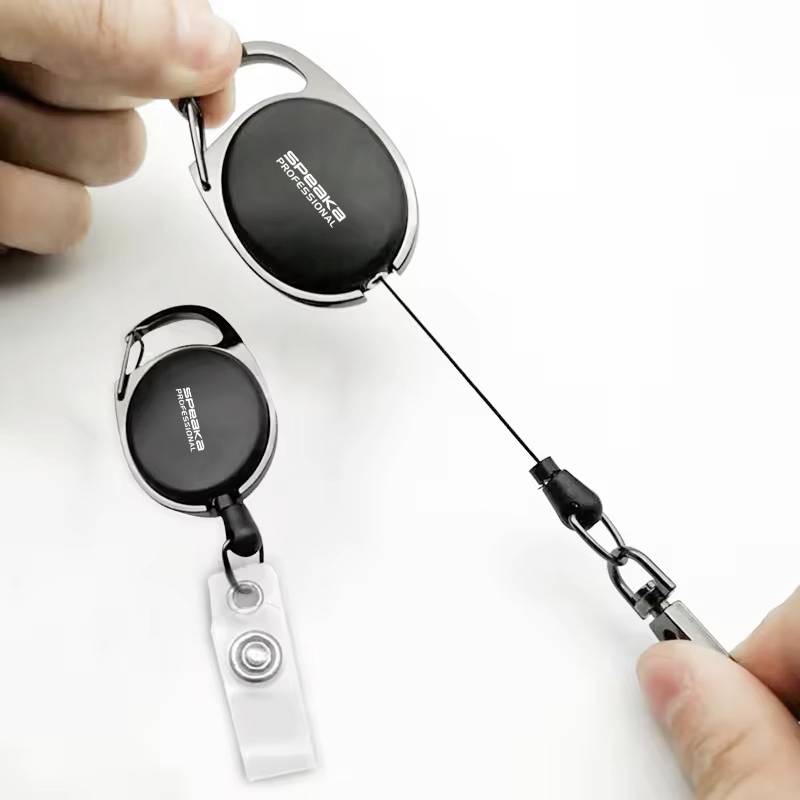 Eine Hand zeigt einen ausziehbaren Schlüsselanhänger mit Clip, der an einer Karte oder einem Ausweis befestigt ist.