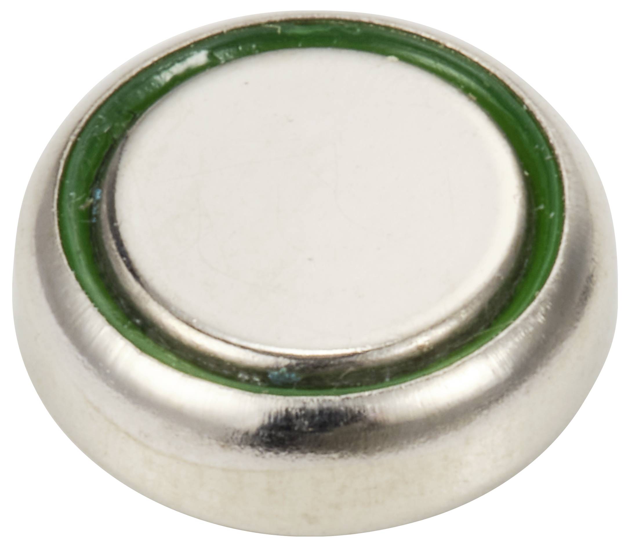 Runder silberner Magnet, umgeben von einem grünen Ring, liegt auf einer weißen Fläche.