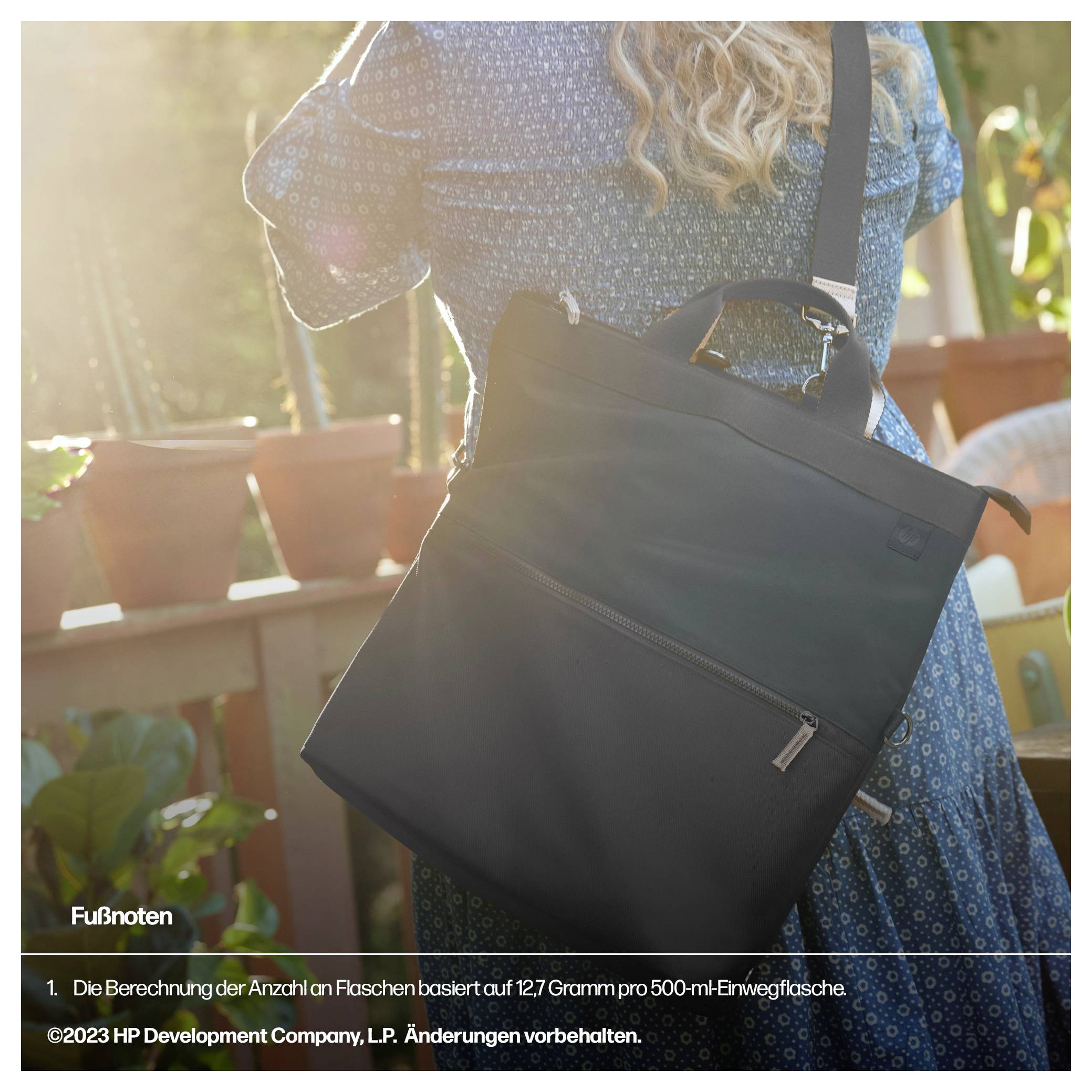 Eine Frau trägt eine schwarze Tasche über der Schulter, während sie in einem sonnigen Garten steht. Im Hintergrund sind Pflanzen sichtbar.