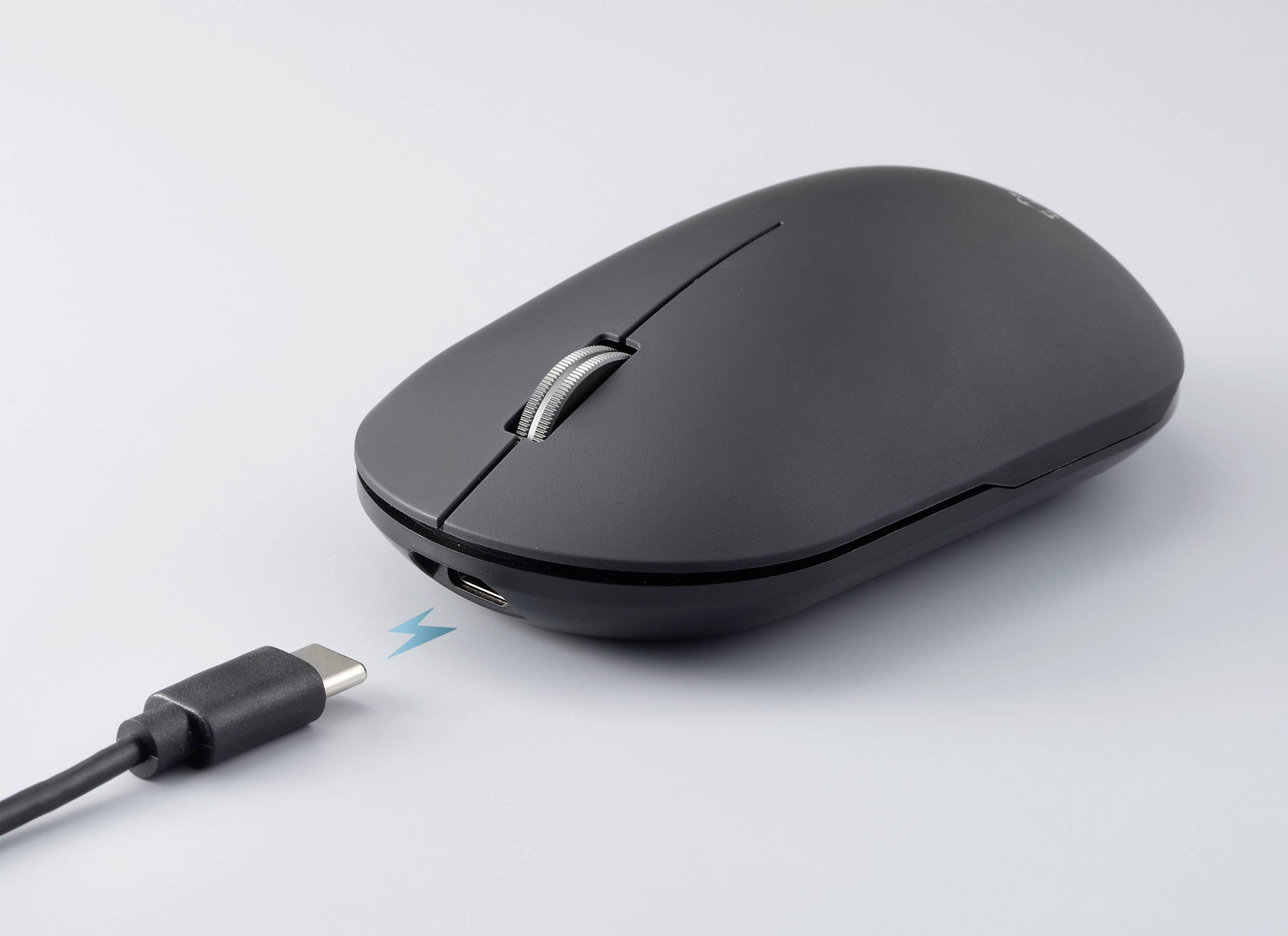 Eine schwarze Computermaus mit USB-C-Ladekabel, das eine Verbindung zur Maus herstellt; symbolisiert das Aufladen der Maus.