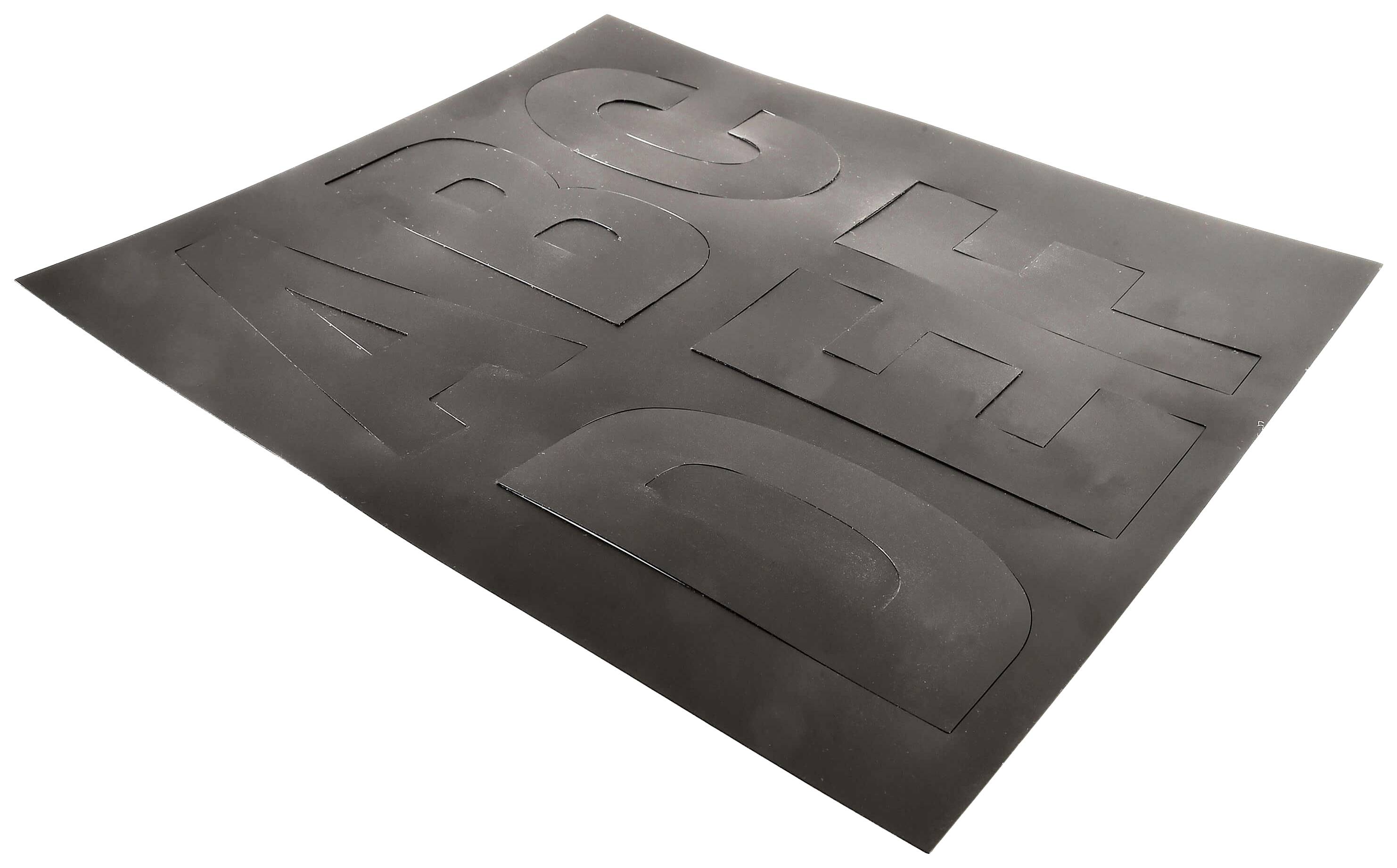 Schwarze Schablone mit ausgeschnittenen Buchstaben 'A', 'B', 'C', 'D', 'E', 'F', leicht schräg liegend, auf weißem Hintergrund.