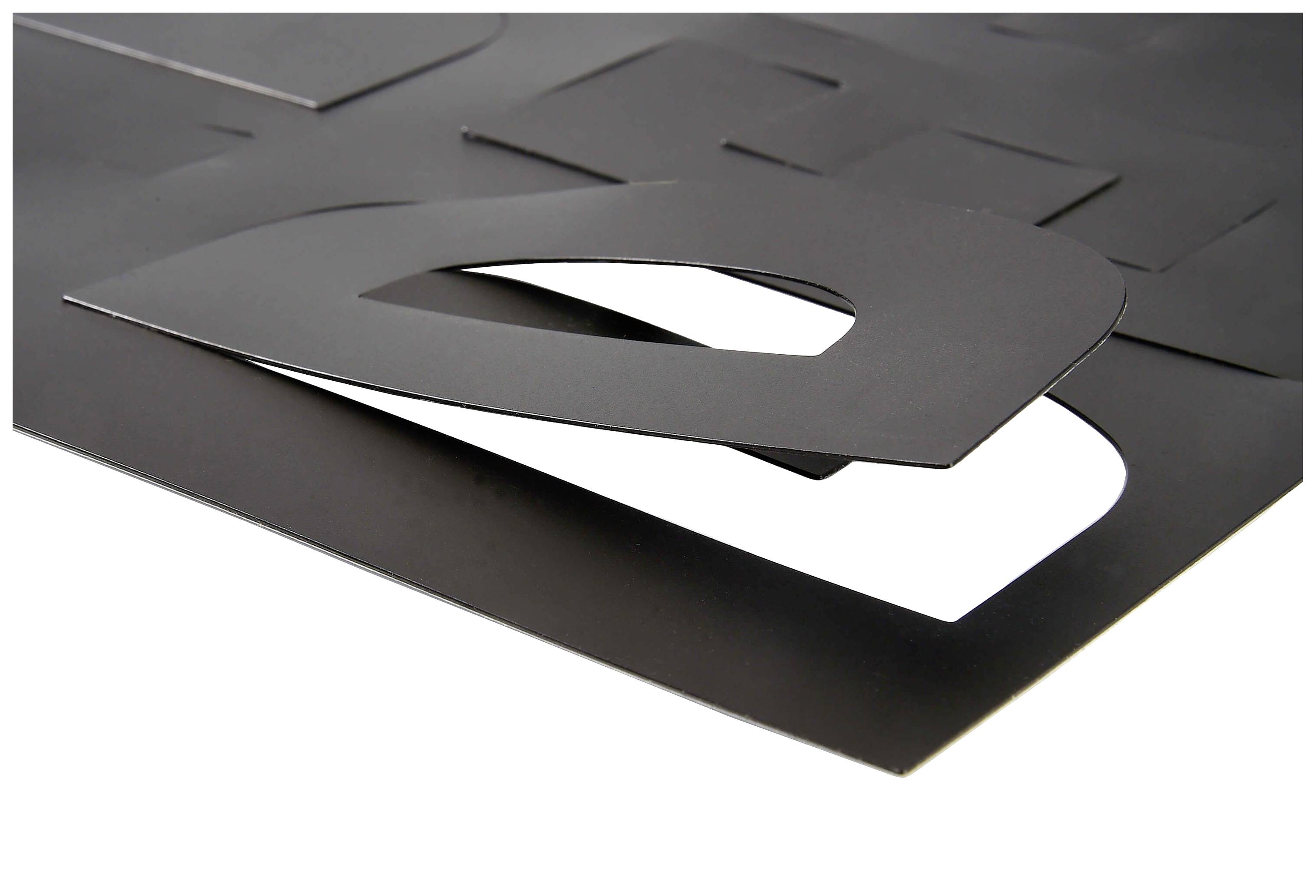 Schwarzes Papier mit ausgestanzter Form eines Buchstaben 'D', das auf einem weißen Hintergrund liegt.