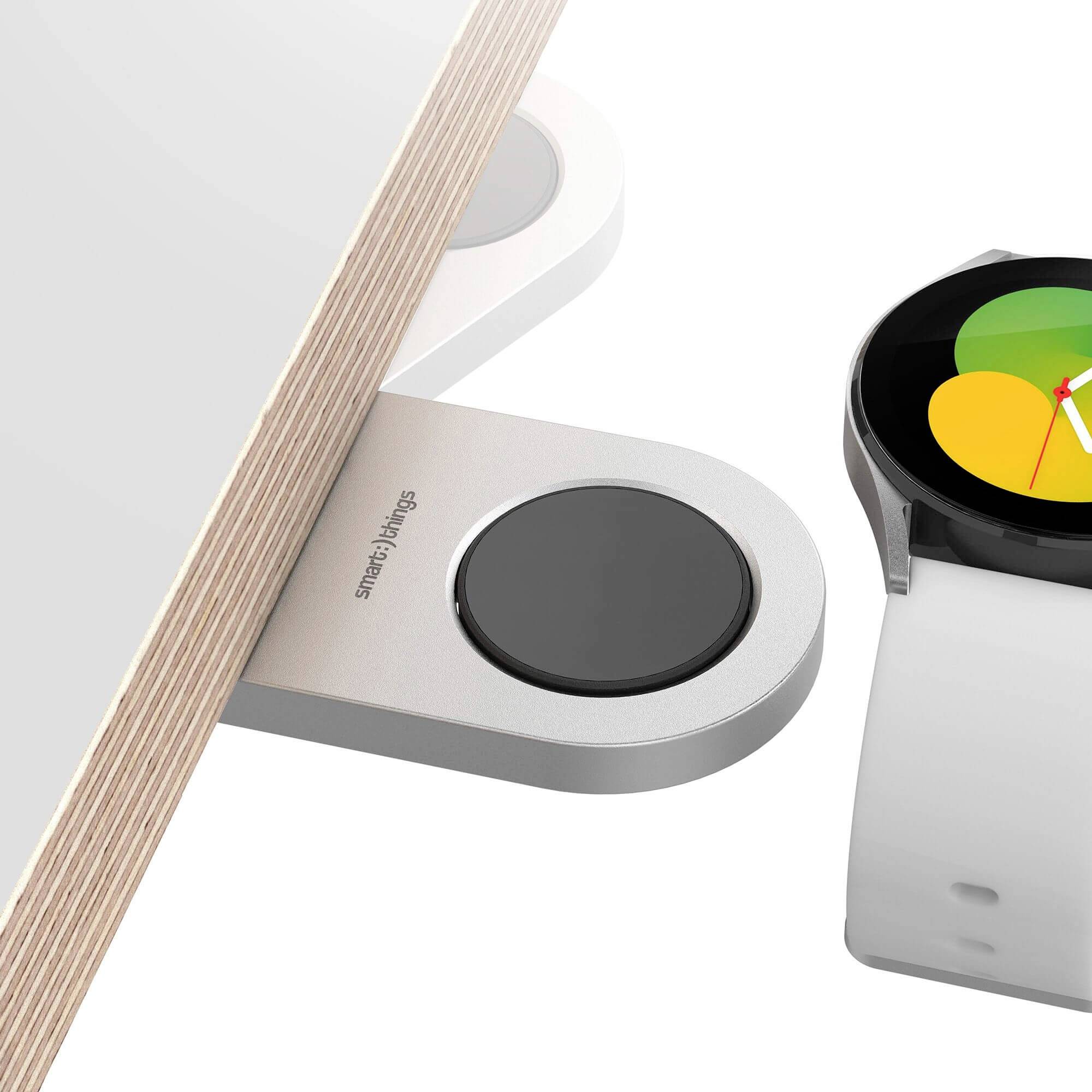 Eine Smartwatch wird über ein kabelloses Ladegerät auf einem Tisch aufgeladen. Sie zeigt eine farbige, kreisförmige Anzeige.