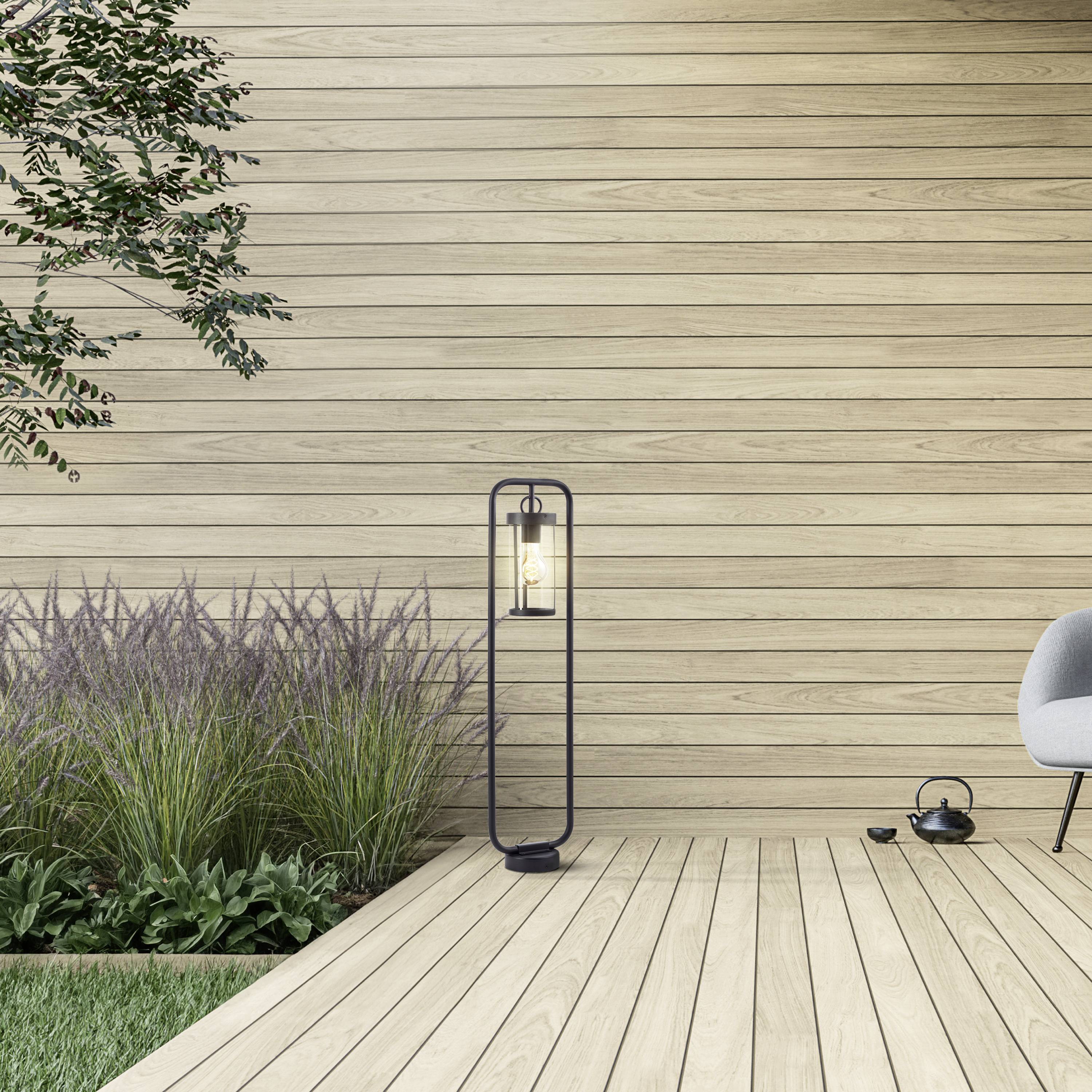 Ein minimalistischer Terrassenbereich mit Holzdielen, einer dekorativen Laterne, einem Baum und einer niedrigen Sitzgelegenheit.