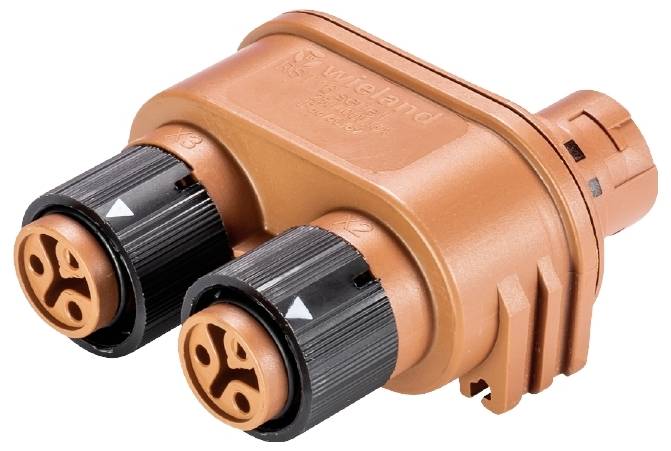 Ein orange-brauner elektrischer Stecker mit zwei schwarzen Anschlüssen und markanten runden Symbolen an der Vorderseite.