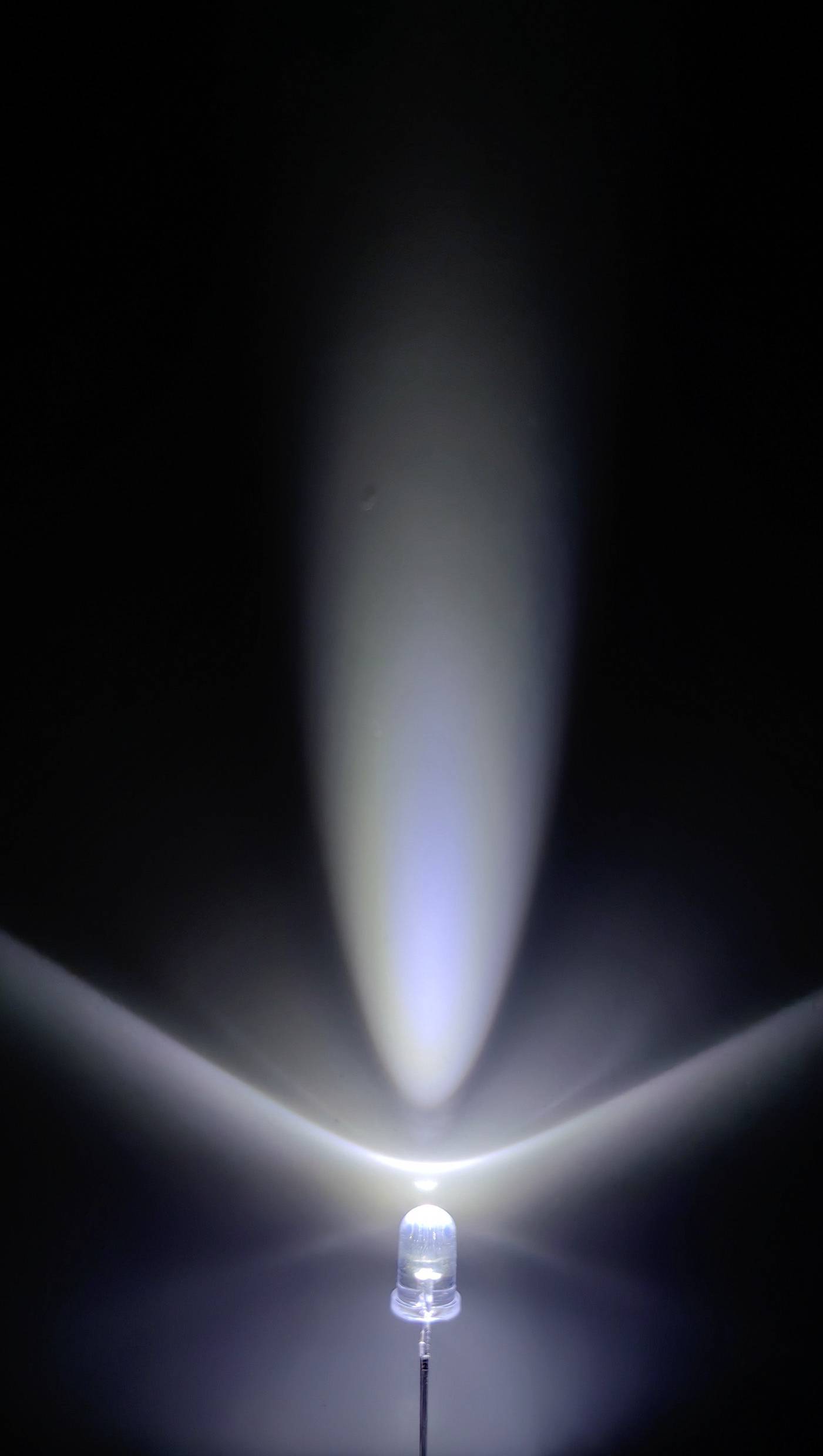 Eine einzelne LED-Leuchte strahlt in einem dunklen Raum, wobei das Licht kegelförmig nach oben abstrahlt und einen leichten blauen Schimmer erzeugt.