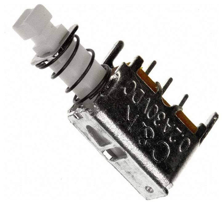 Eine kleine metallische Komponente mit mehreren Stiften und einem weißen zylindrischen Abschnitt, wahrscheinlich ein elektronischer Schalter oder Stecker.
