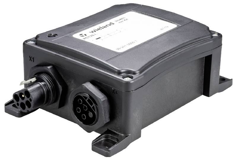 Schwarzes elektrisches Bauteil mit Anschlüssen auf beiden Seiten. Oben befindet sich ein Etikett mit technischen Spezifikationen.