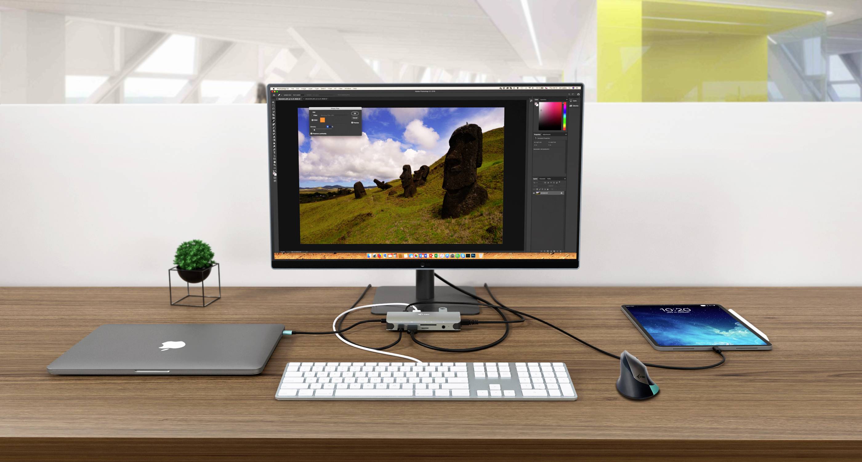 Ein Schreibtisch mit einem Monitor, der ein Bildbearbeitungsprogramm zeigt. Daneben ein Laptop, eine Tastatur, eine Maus und ein Tablet.