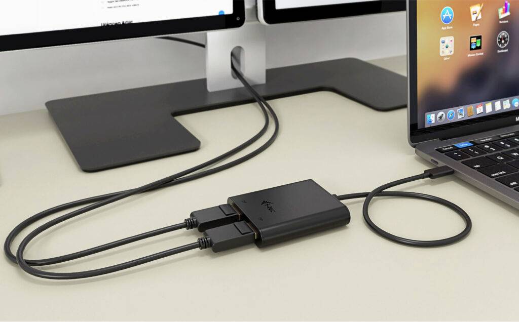 Ein USB-Hub verbindet einen Laptop mit zwei Monitoren auf einem Schreibtisch. Die Kabel verlaufen ordentlich entlang der Arbeitsfläche.