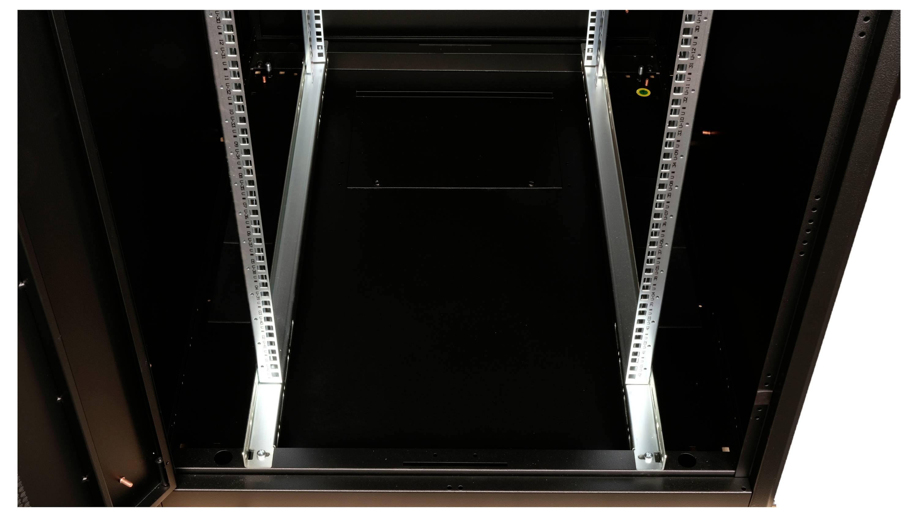 Leerer Server-Rack mit sichtbaren Schienen in einem dunklen Raum.