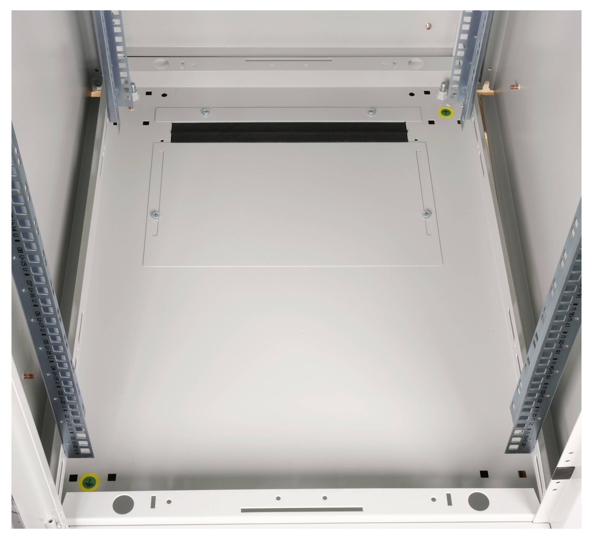 Metallisches Gehäuseinnere eines leeren Schaltschrankes mit Montageschienen an den Seiten und Öffnungen für Kabel oben.