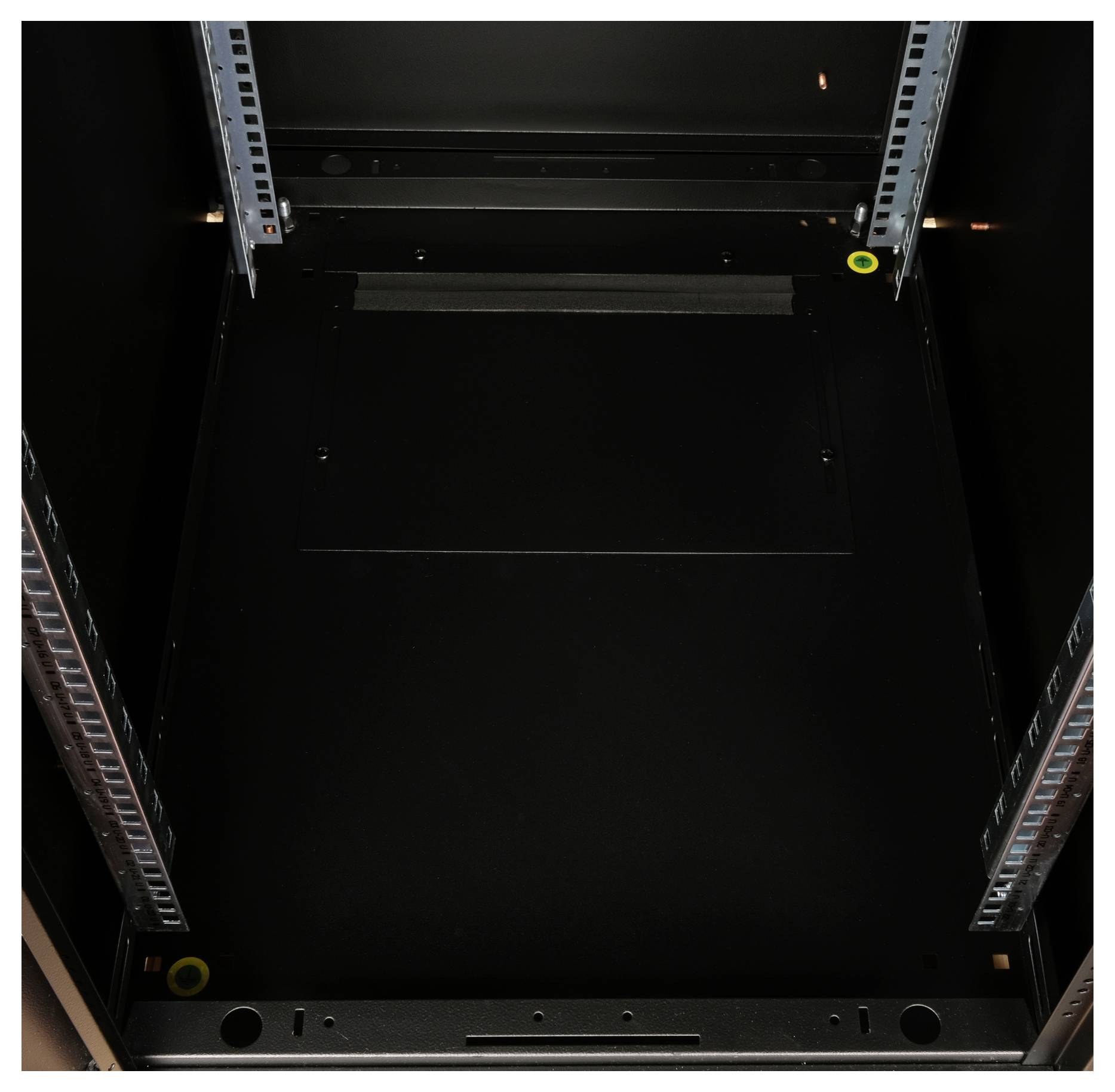 Leerer Serverschrank mit sichtbaren Schienen und zwei gelben Markierungen in den Ecken.