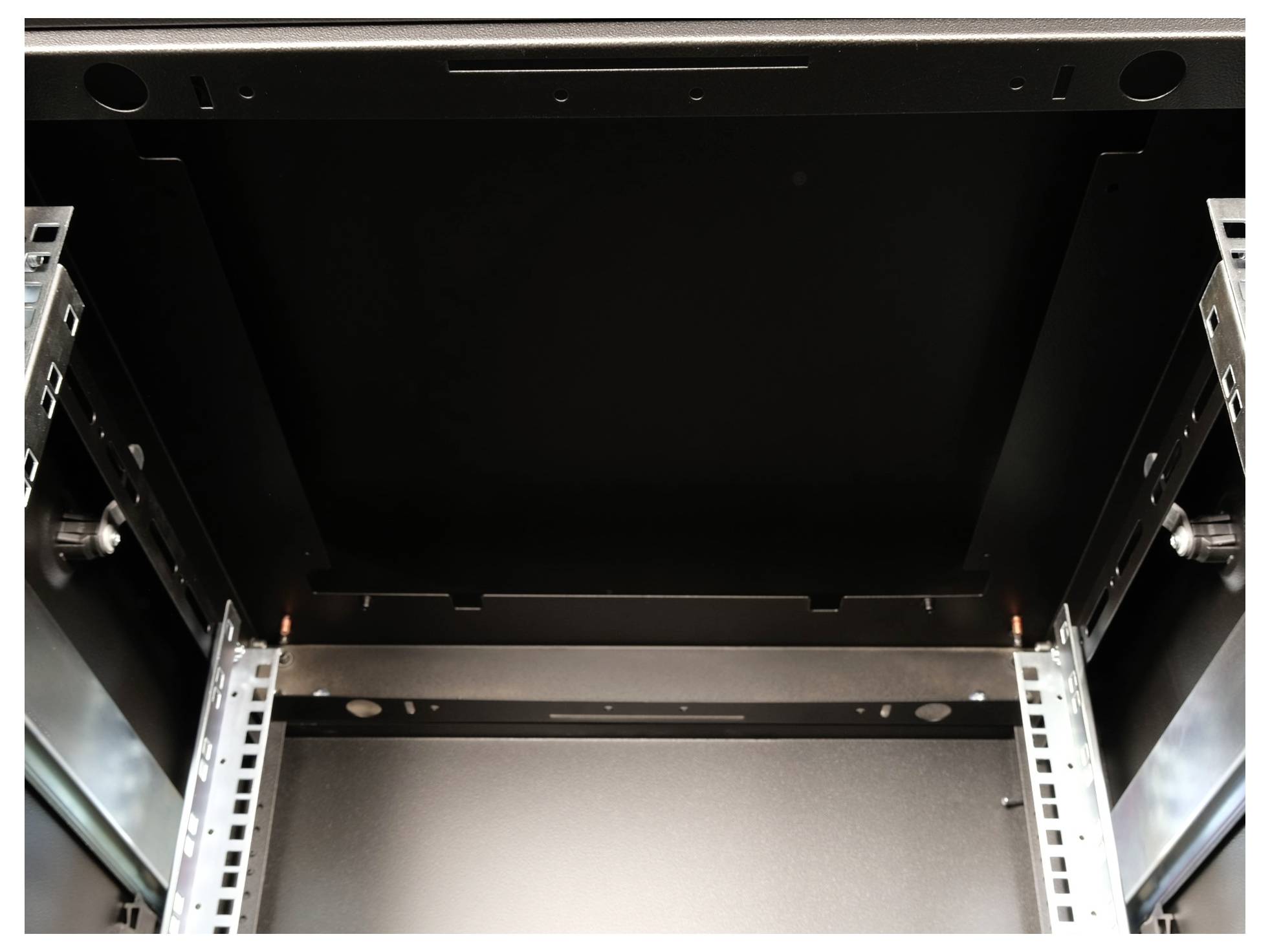 Innenansicht eines leeren schwarzen Serverracks mit Metallrahmen und Schienen an den Seiten.